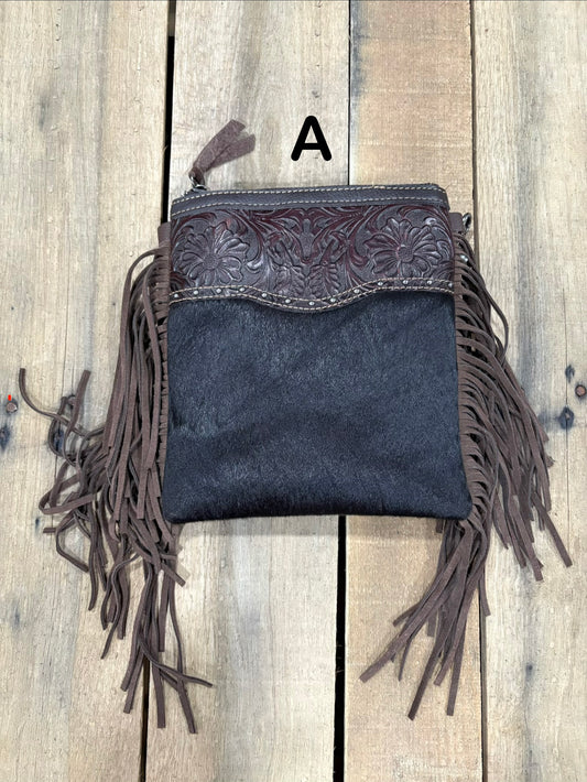 Coffee Brown handbag with hairon cowhide and leather accents and fringes on a wooden surface