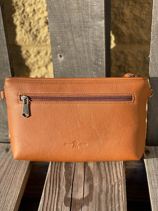 Brown leather clutch bag with zipper pocket on a wooden surface