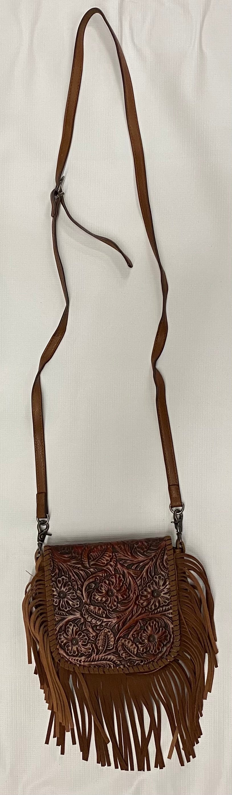 Brown leather crossbody bag with intricate designs and fringes on a white background
