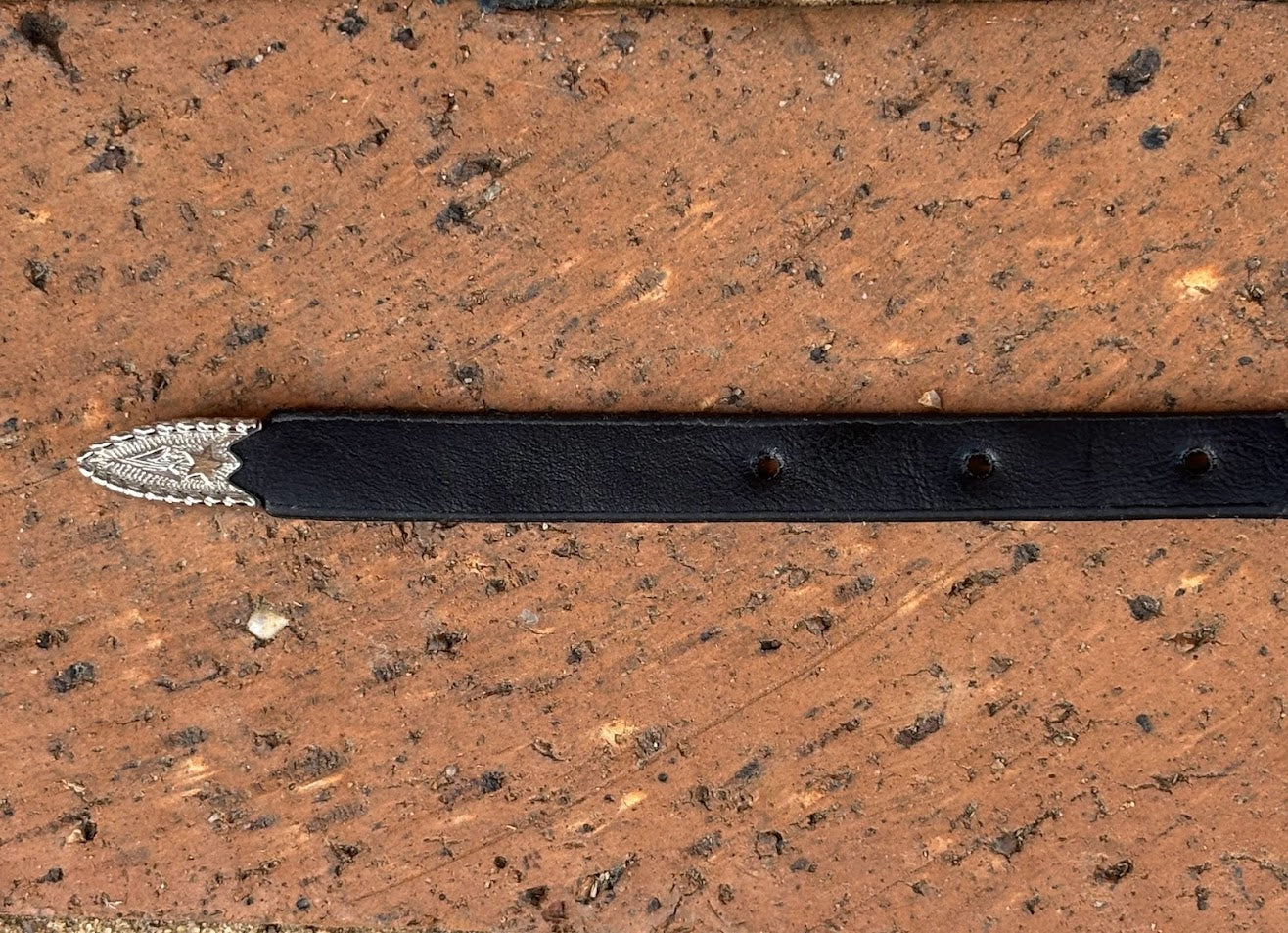 Black leather hat band with a Bull Rider Concho separated by Silver bands. Close up view of tip.
