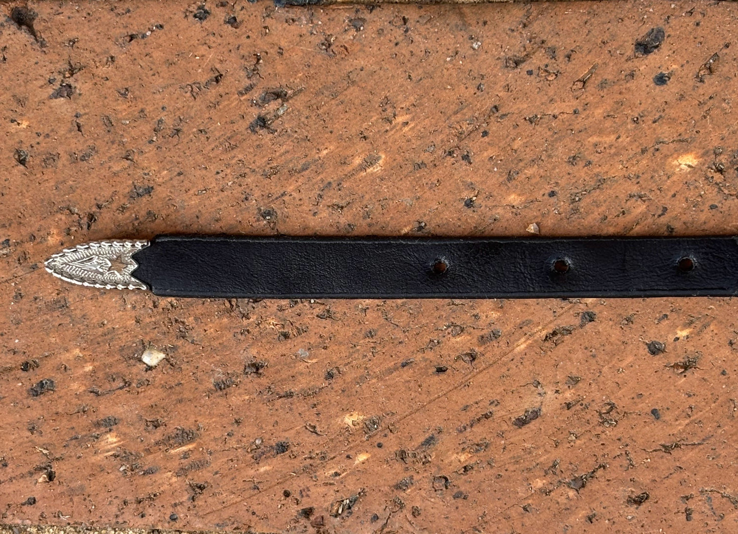 Black leather hat band with a Horse Head Concho with silver bands separating them. This hat band is fully adjustable with a Western style buckle. Close up view of end.