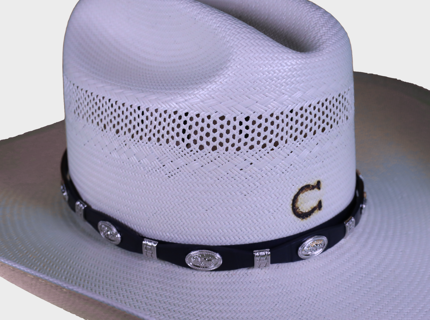 Black leather hat band with Praying Cowboy Conchos and a Western style buckle closure. Front view showing band on straw hat.