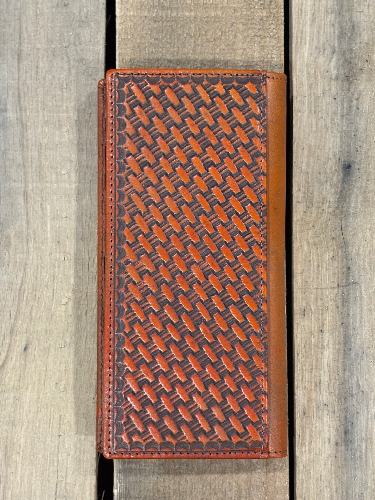 Brown leather wallet with woven pattern on a wooden surface