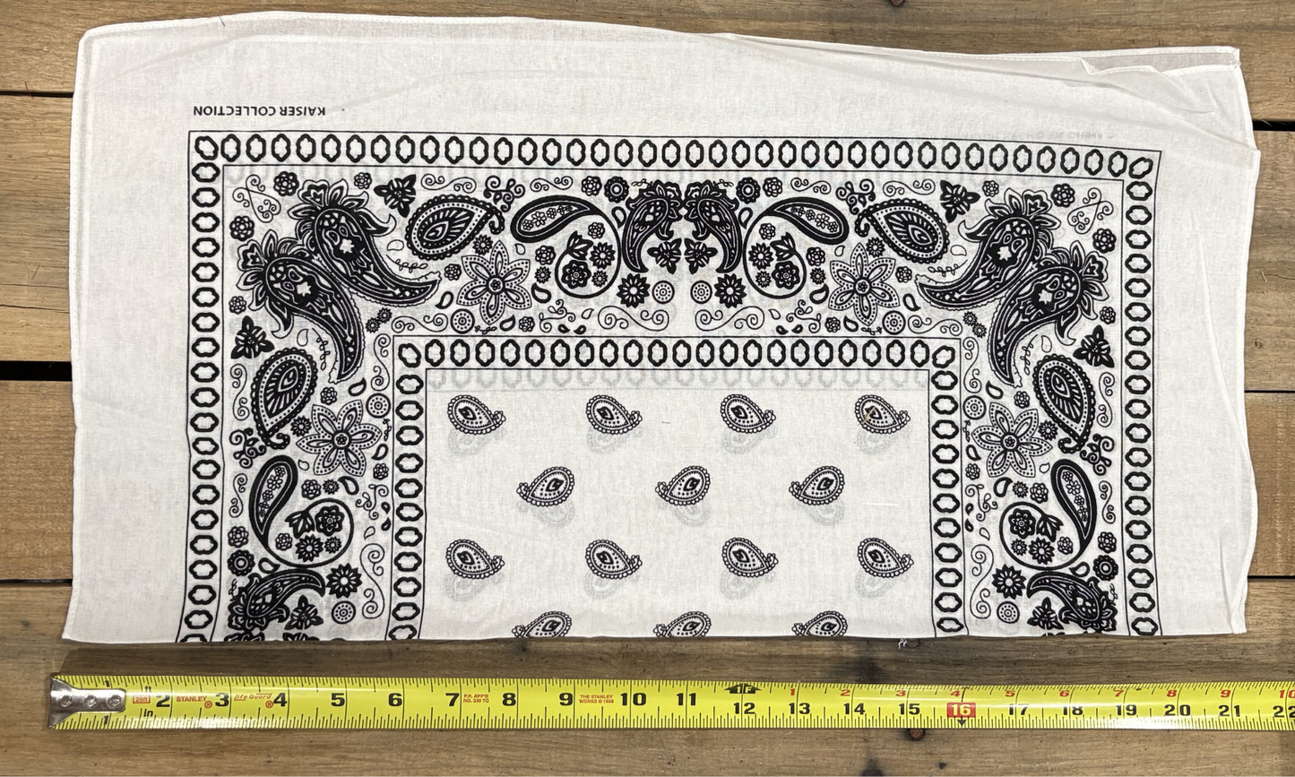 White bandana with white paisley patterns on a wooden surface, measured by a yellow tape measure.