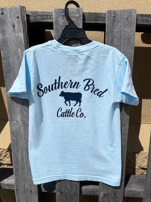 Light blue t-shirt with 'Southern Bred Cattle Co.' Navy text and cow graphic on a wooden background