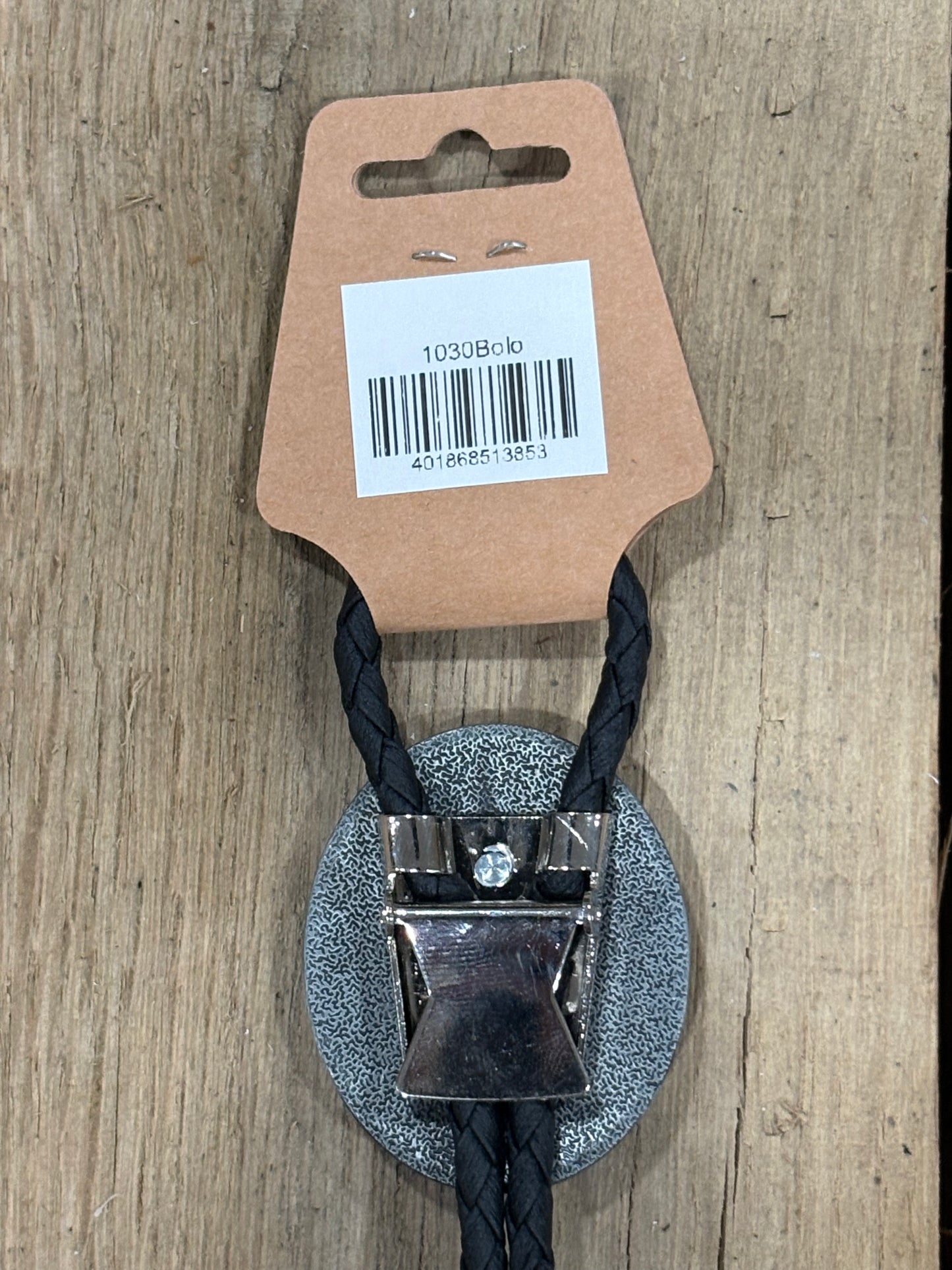Metal clip with black cord on a cardboard backing with a barcode on a wooden surface