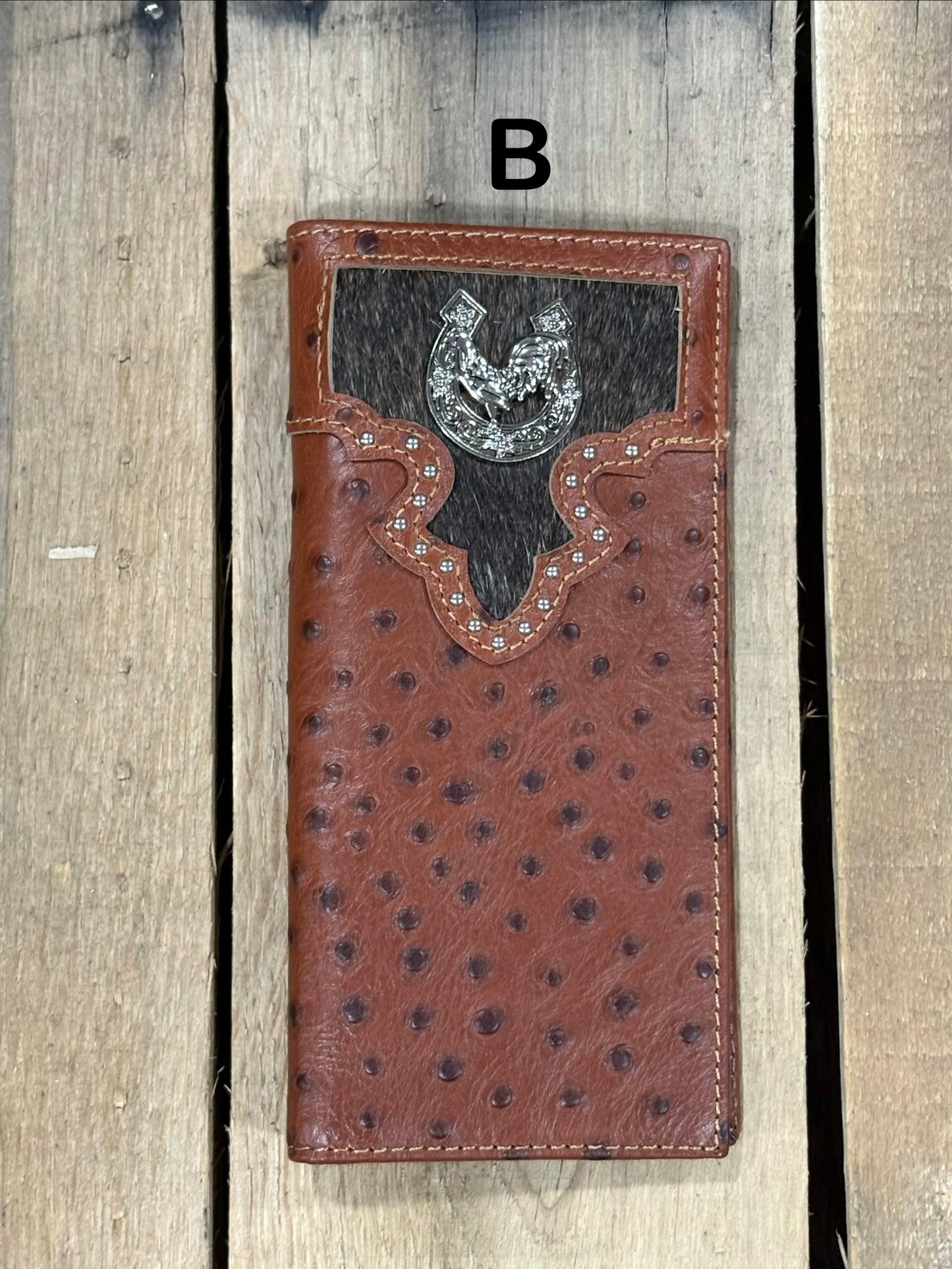 Brown leather wallet with cowhide pattern and horseshoe and rooster concho on a wooden surface