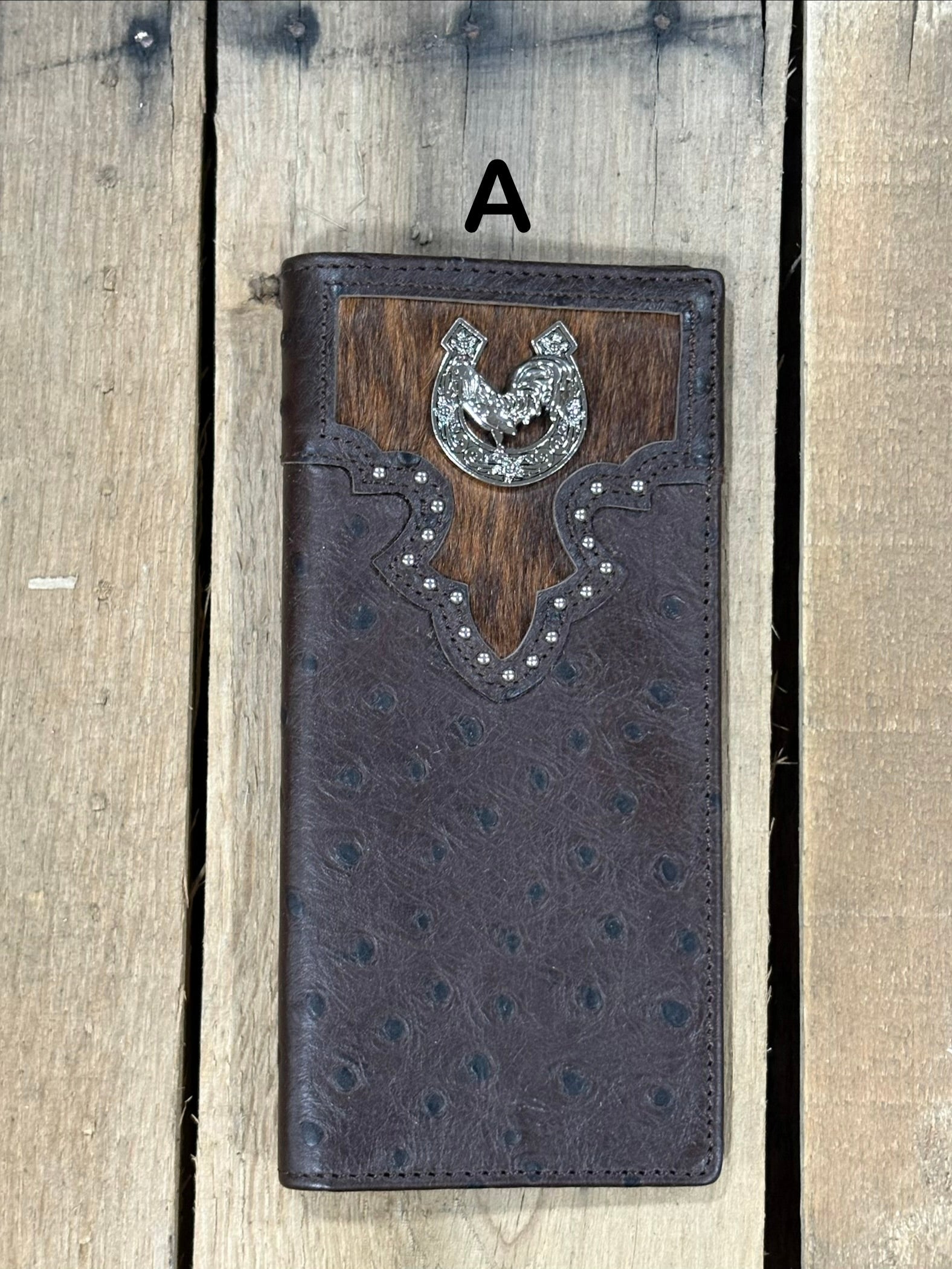 Coffee brown leather wallet with cowhide pattern and horseshoe and rooster concho on a wooden surface