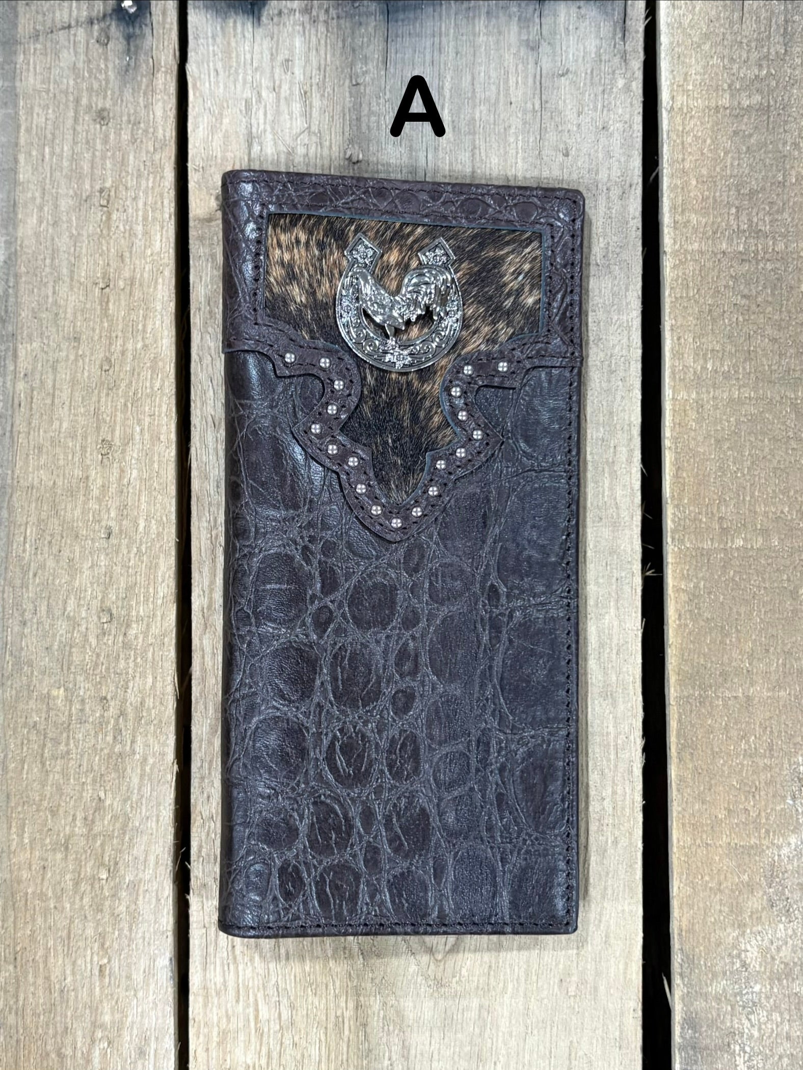 Coffee brown leather wallet with cowhide pattern and horseshoe and rooster concho on a wooden surface