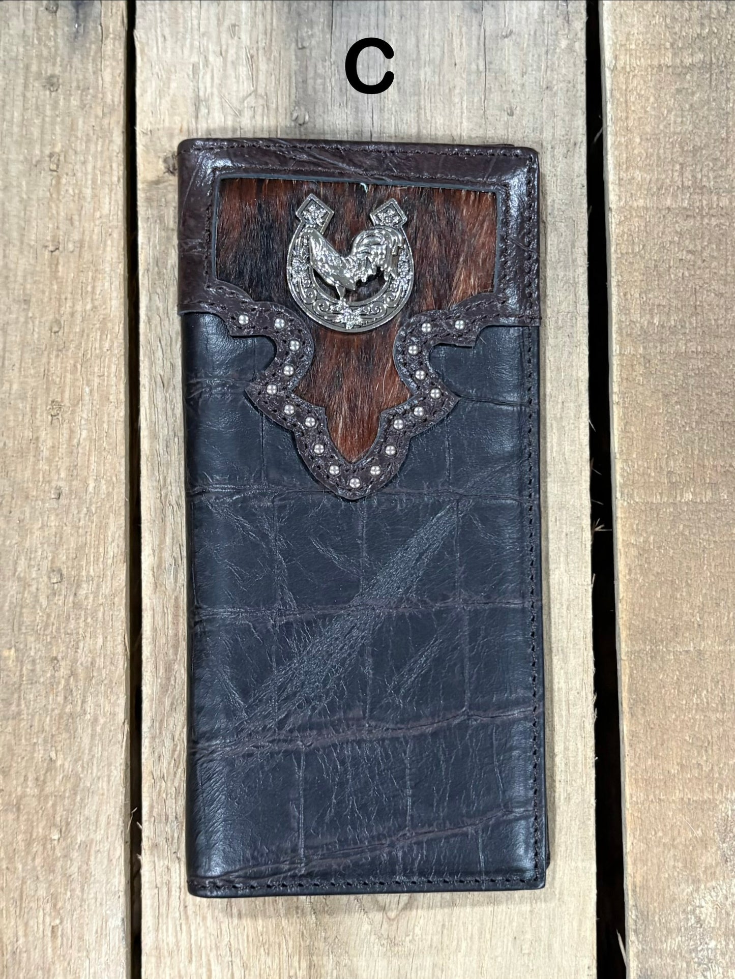 Coffee brown leather wallet with cowhide pattern and horseshoe and rooster concho on a wooden surface
