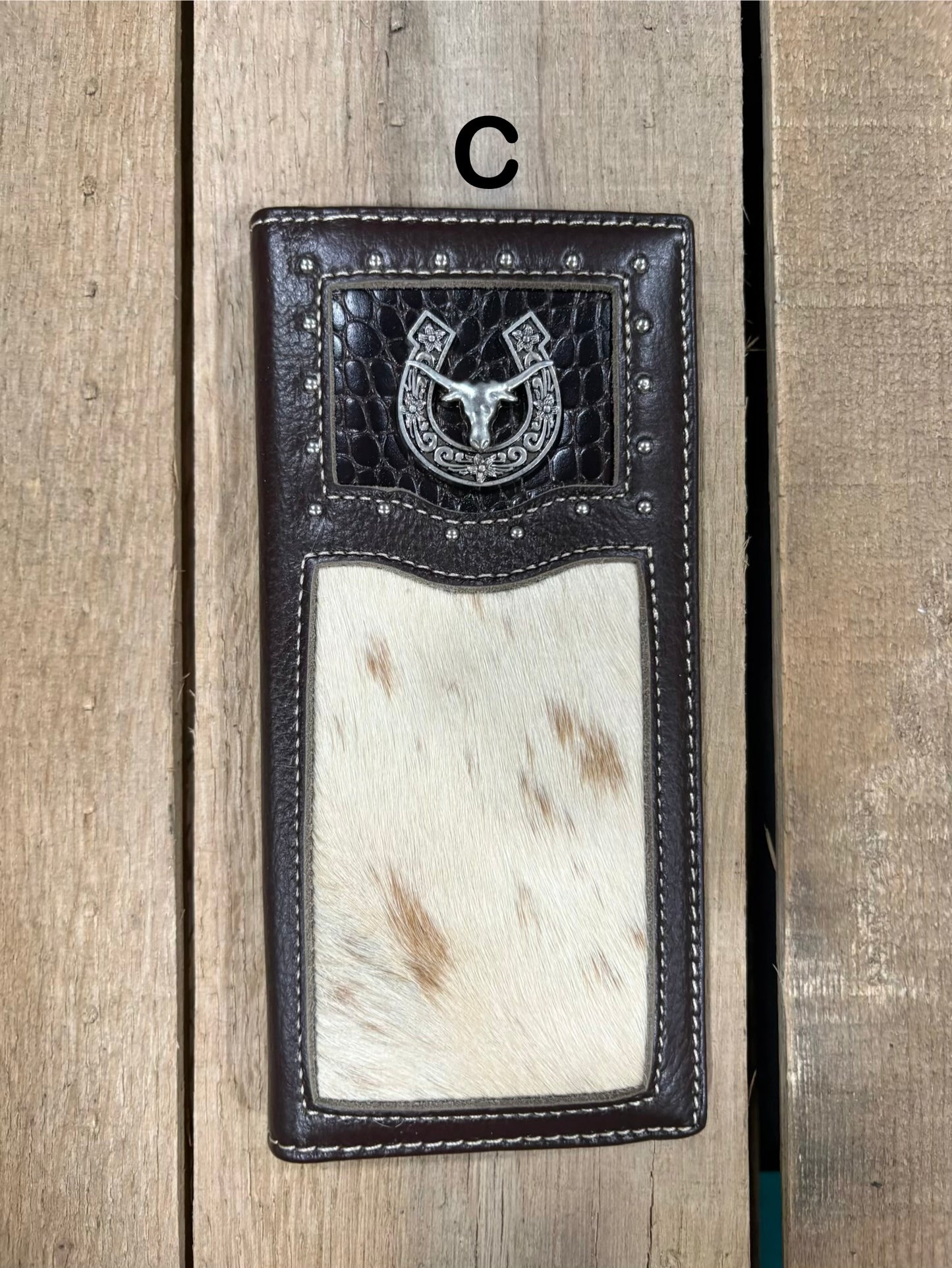 Coffee brown leather wallet with horseshoe and longhorn concho design on a wooden surface