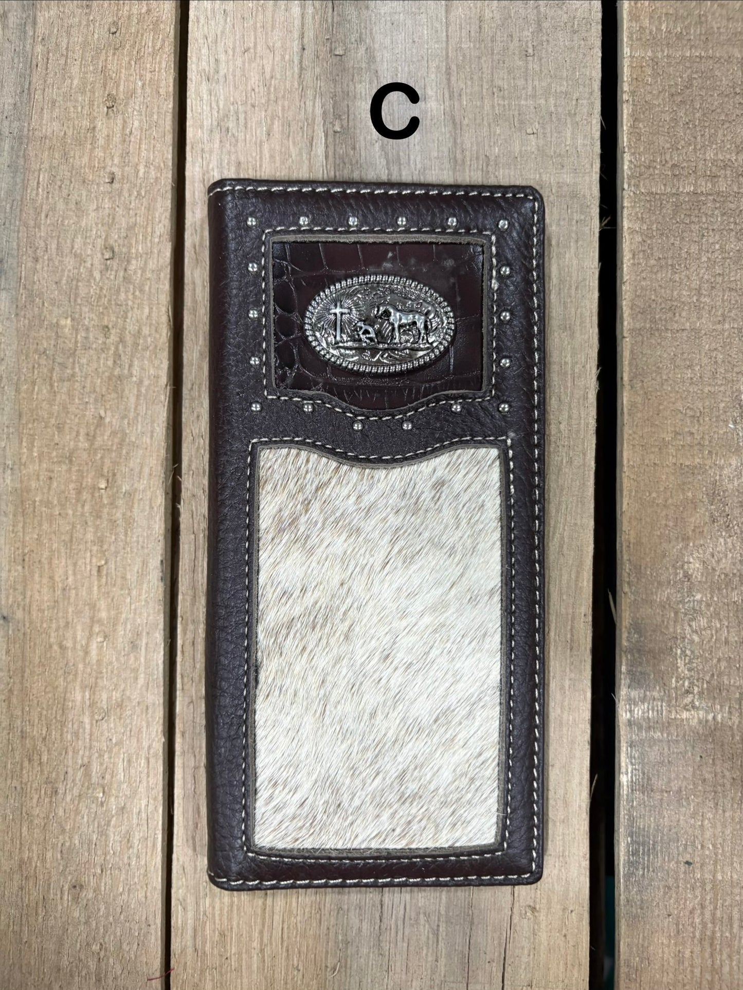 Coffee brown leather wallet with praying cowboy concho design on a wooden surface