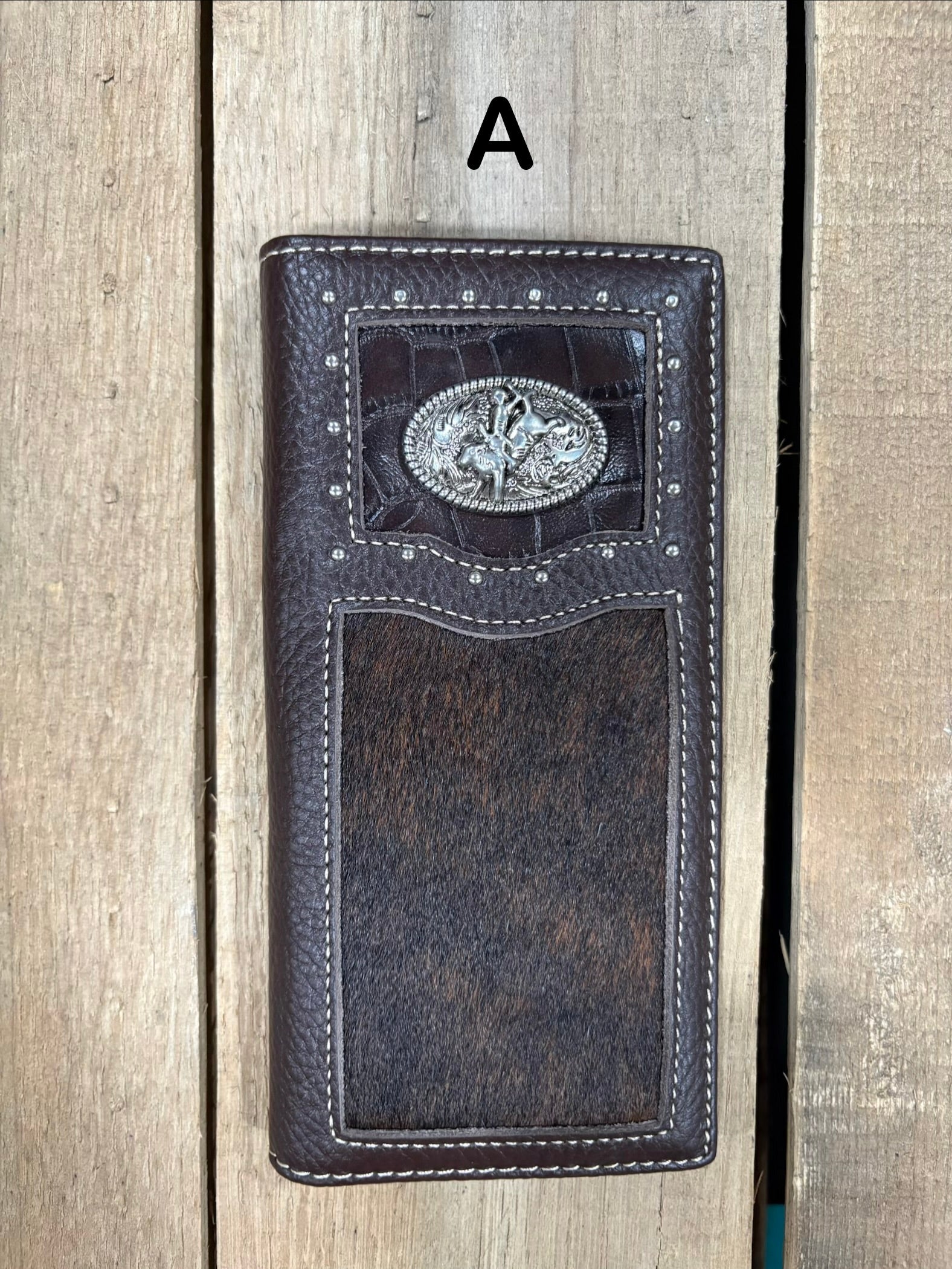 Coffee brown leather wallet with bull rider concho design on a wooden surface