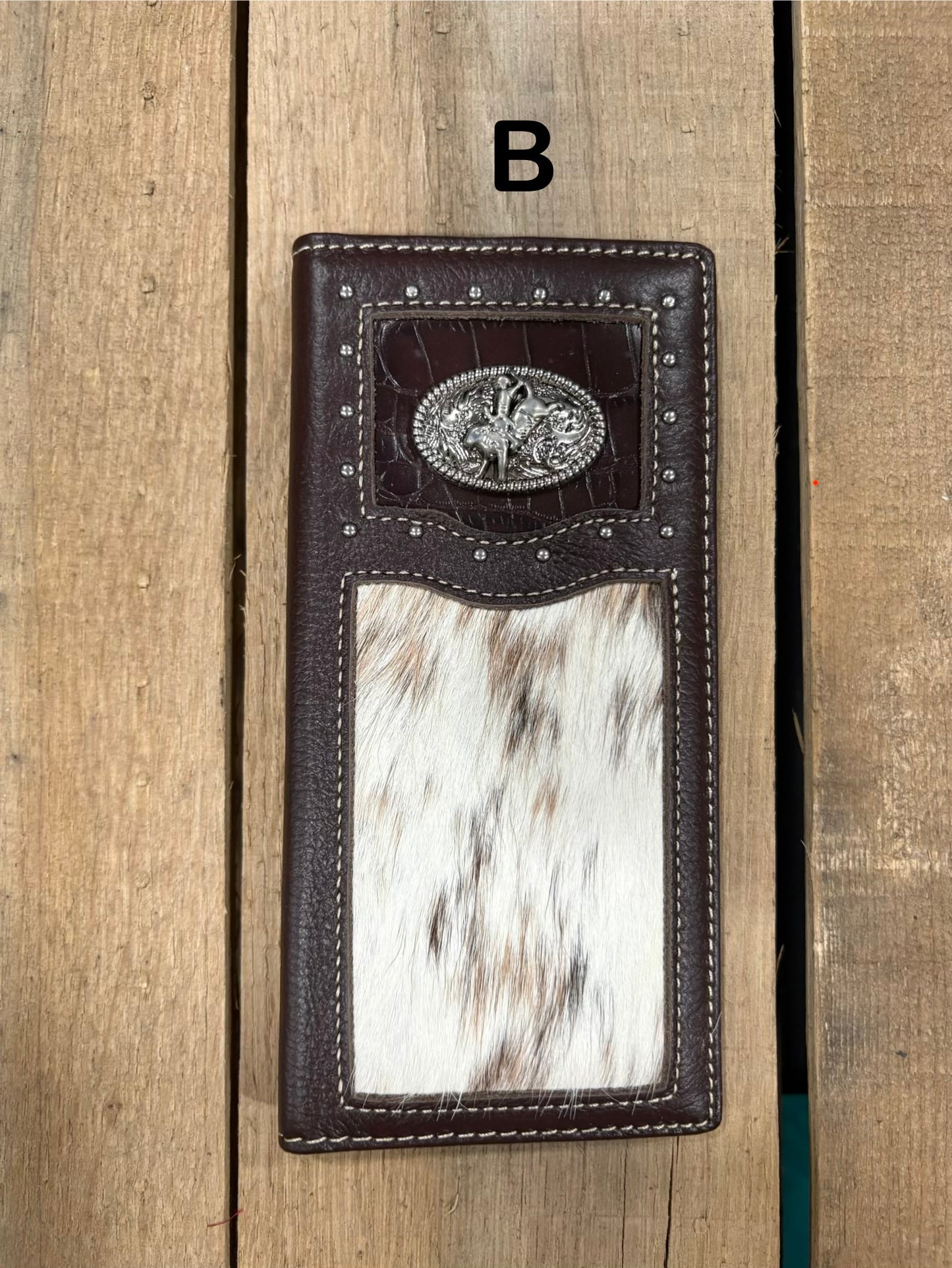 Coffee brown leather wallet with bull rider concho design on a wooden surface