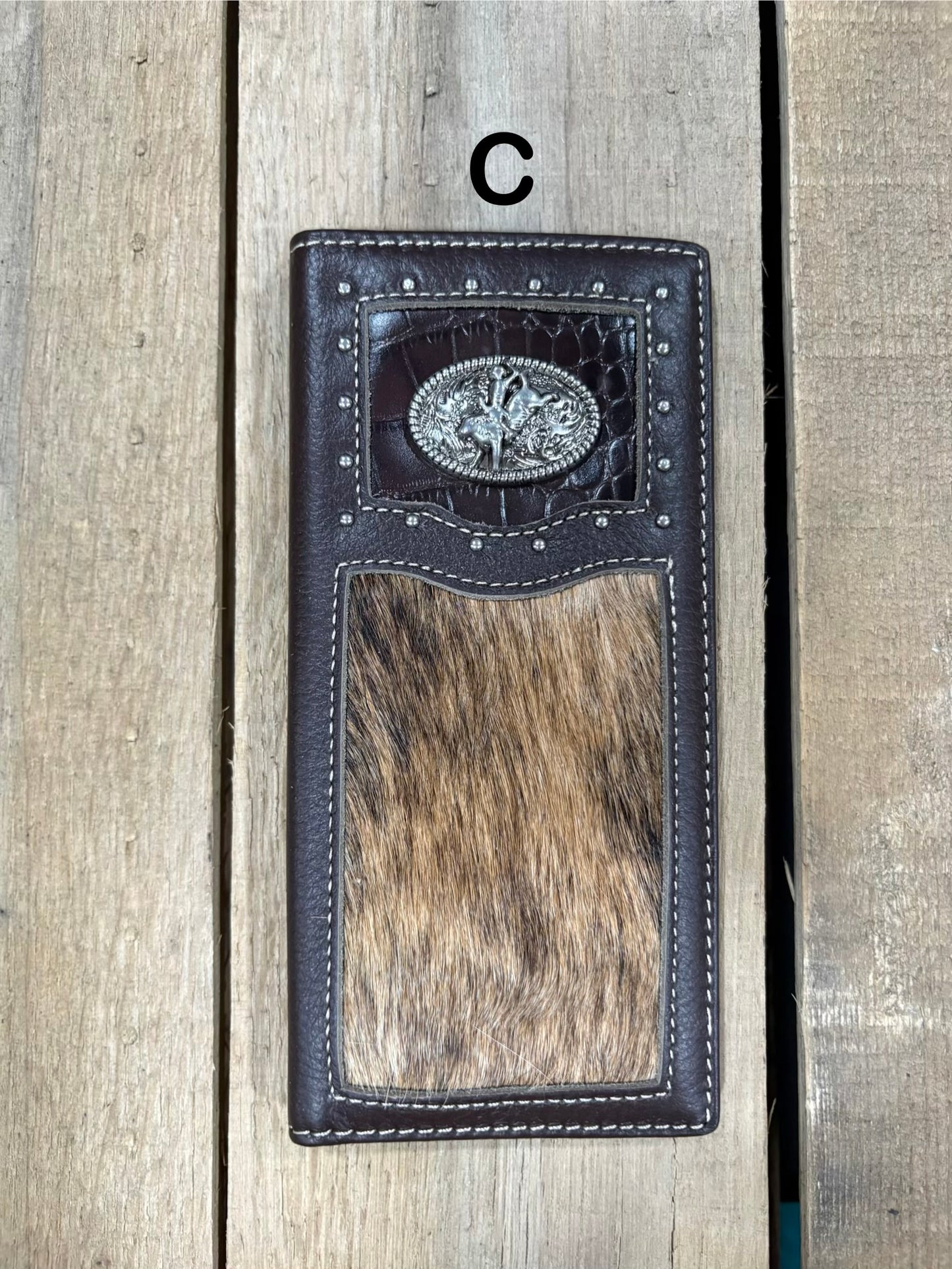 Coffee brown leather wallet with bull rider concho design on a wooden surface