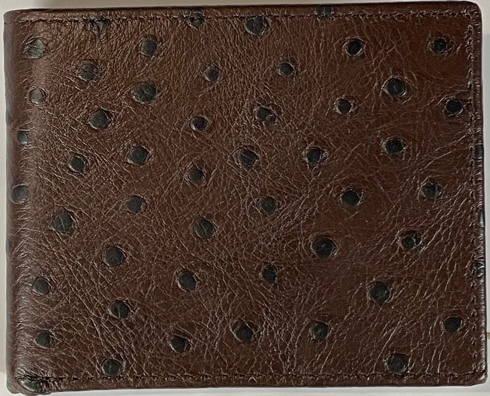 Close up of a Coffee Brown leather wallet with a subtle pattern on a white background