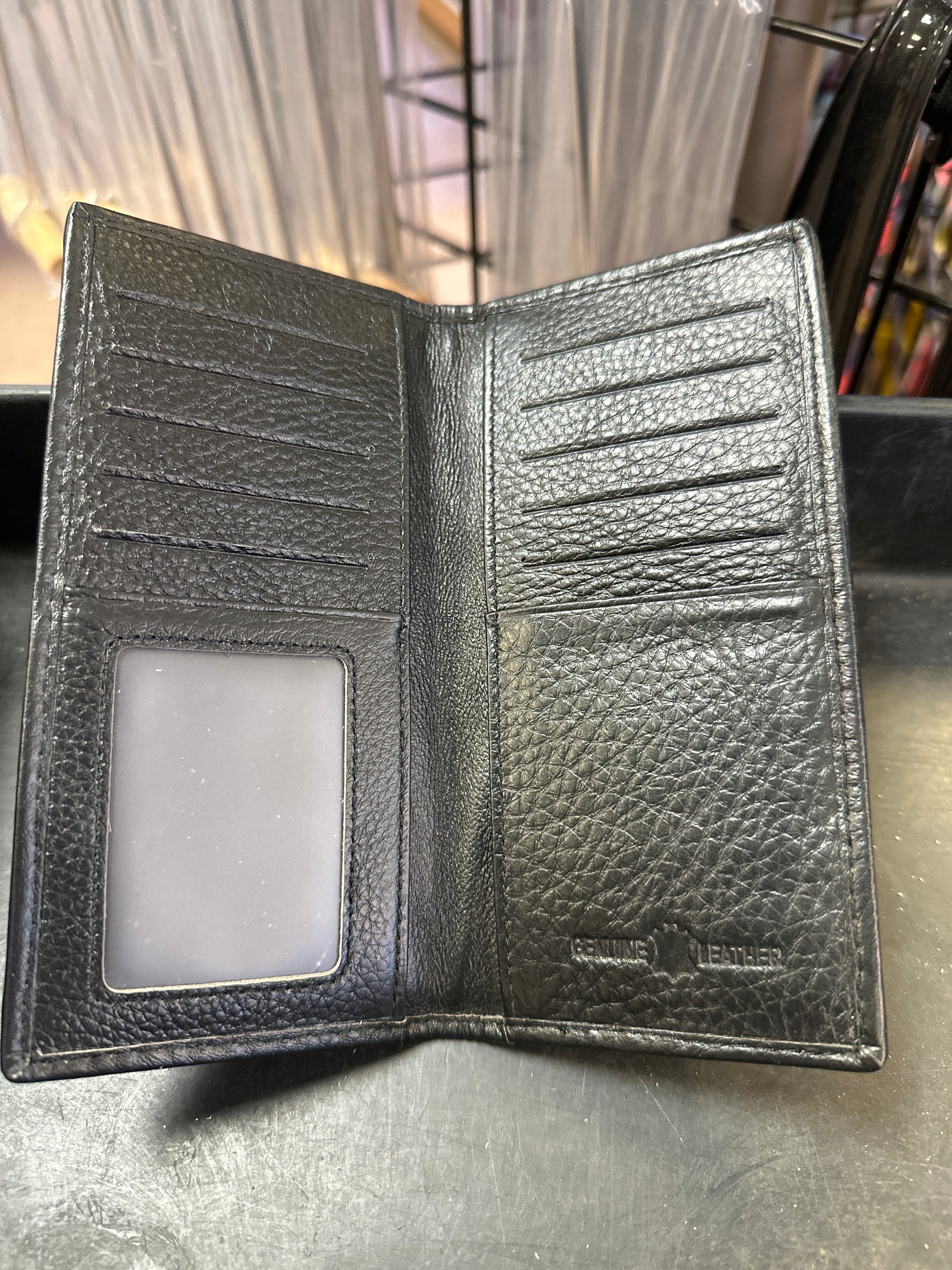 Black leather wallet with a card holder on a metallic surface