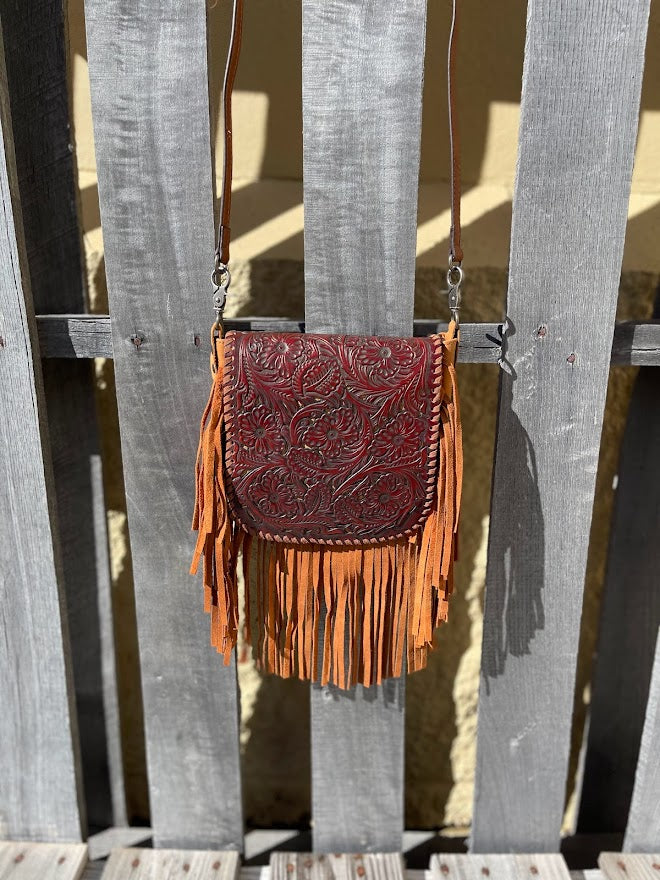This Brown leather crossbody bag features fringe sides and a tooled flap with a whipstitch border. It has a removable and adjustable shoulder strap. Front View