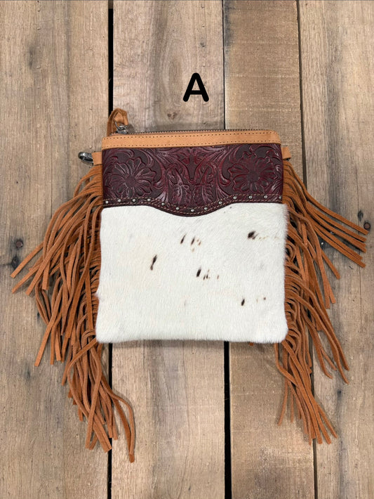 Brown handbag with hairon cowhide and leather accents and fringes on a wooden surface