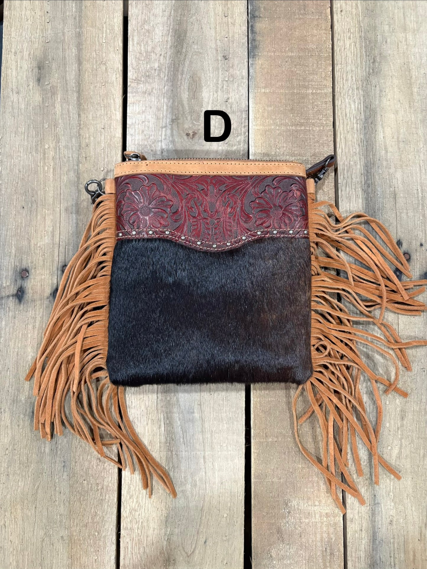 Brown handbag with hairon cowhide and leather accents and fringes on a wooden surface