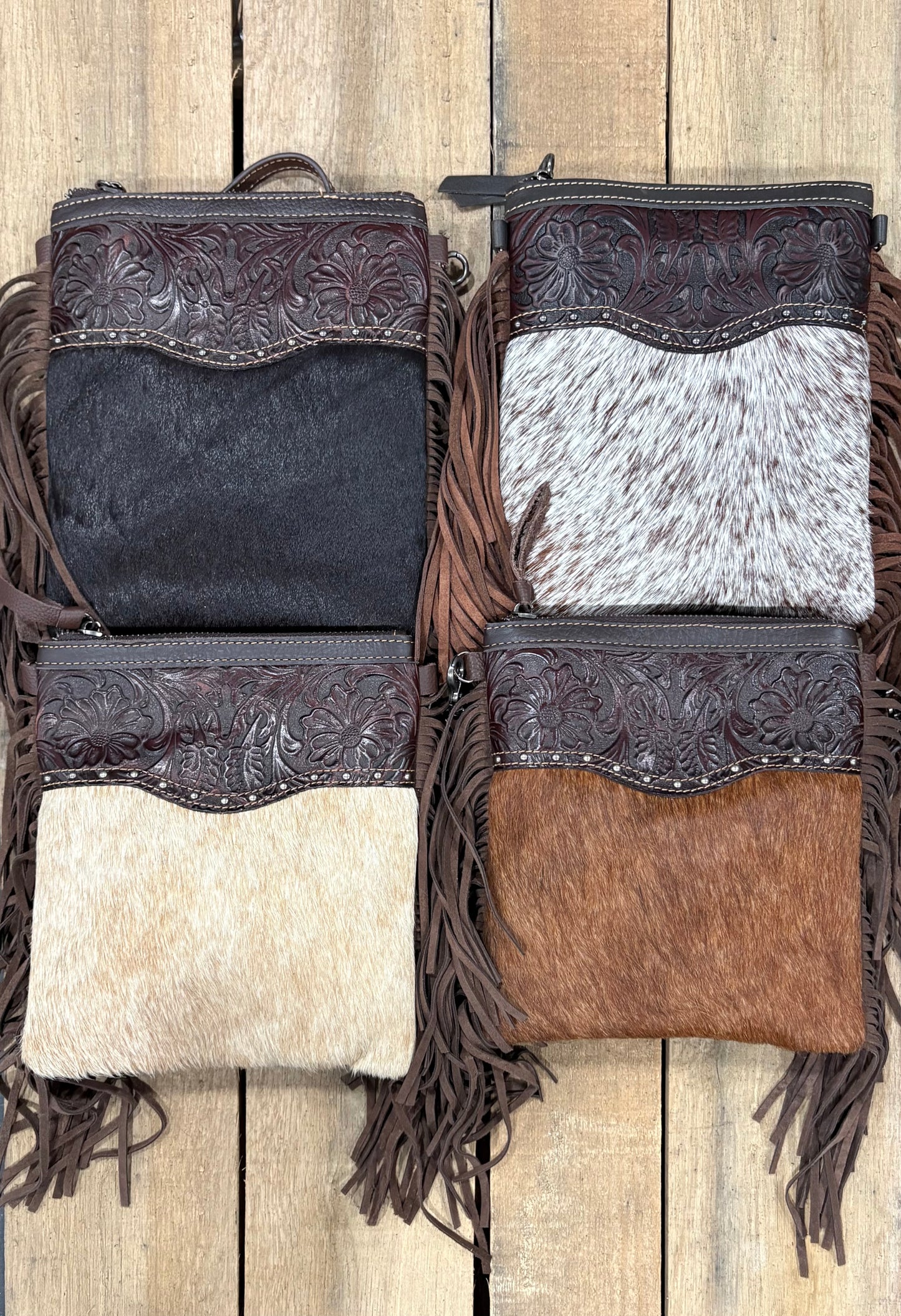 Four handbags with hairon intricate designs and fringes on a wooden surface