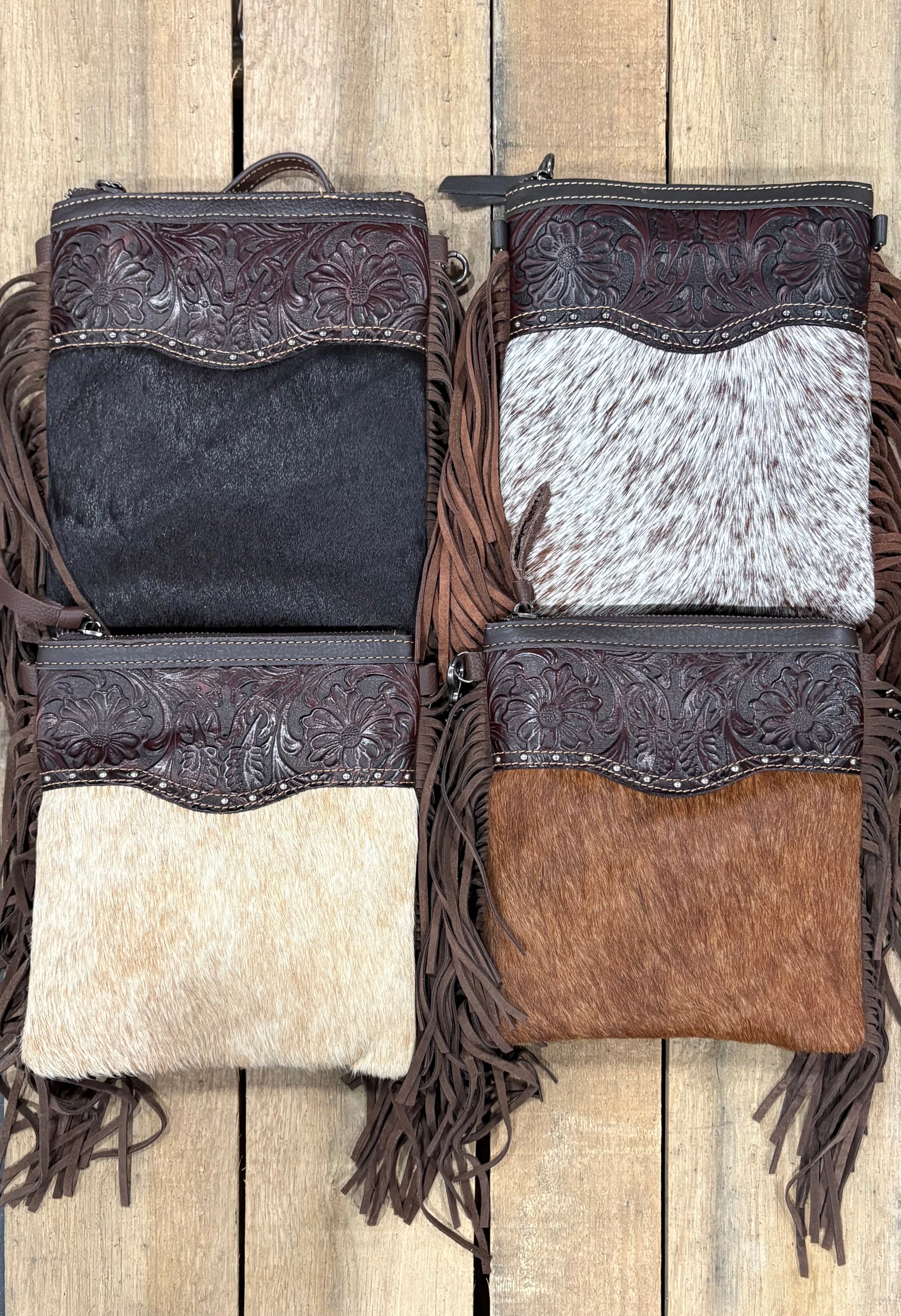Four handbags with hairon intricate designs and fringes on a wooden surface