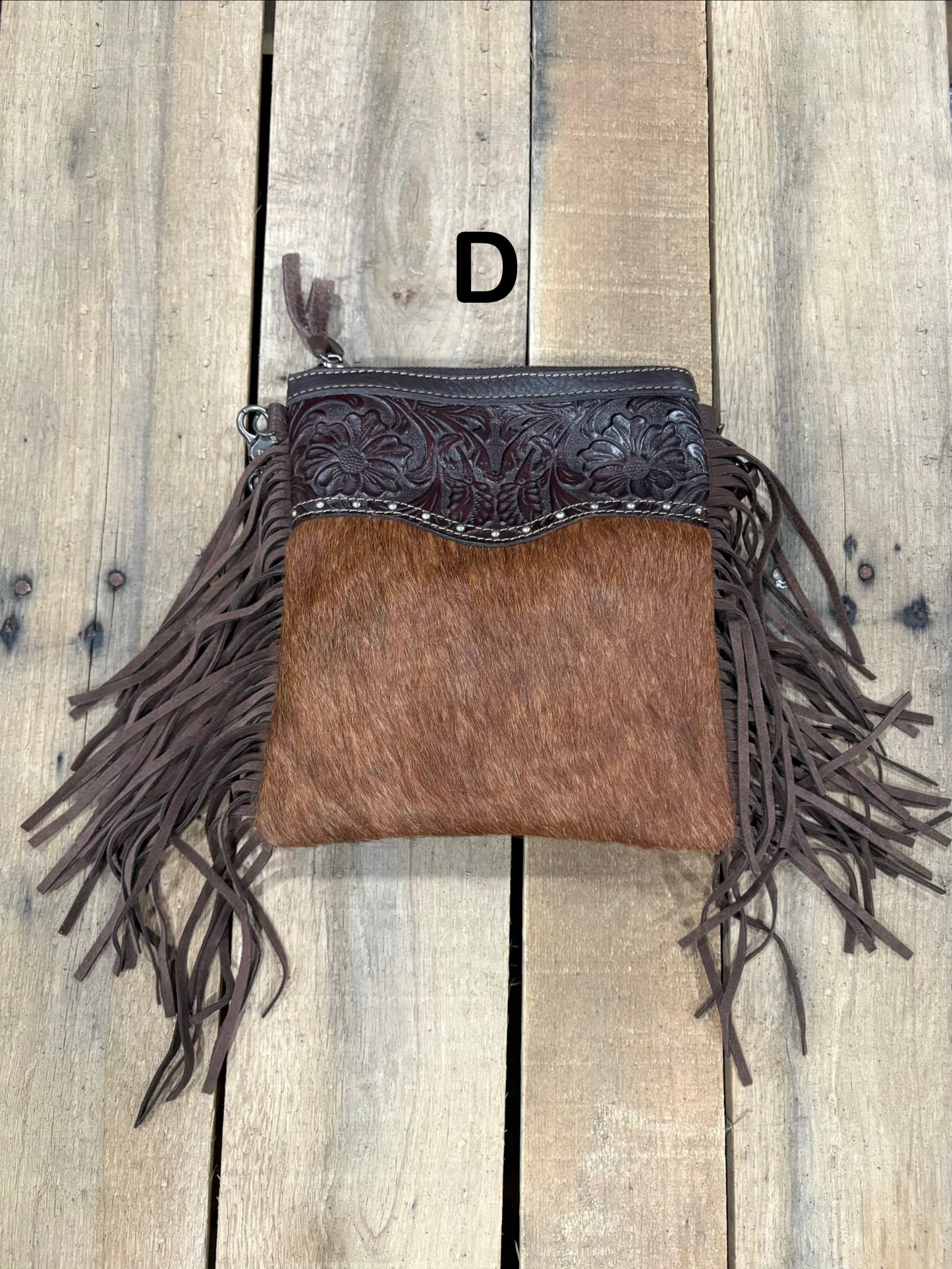 Coffee Brown handbag with hairon cowhide and leather accents and fringes on a wooden surface