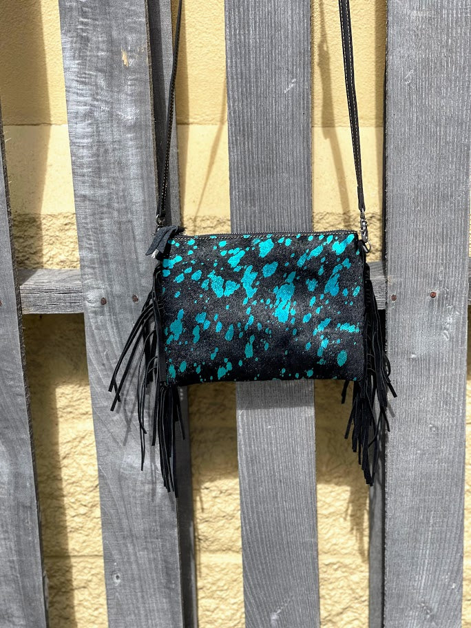 Black clutch with Turquoise speckles and black fringe on a wooden background.