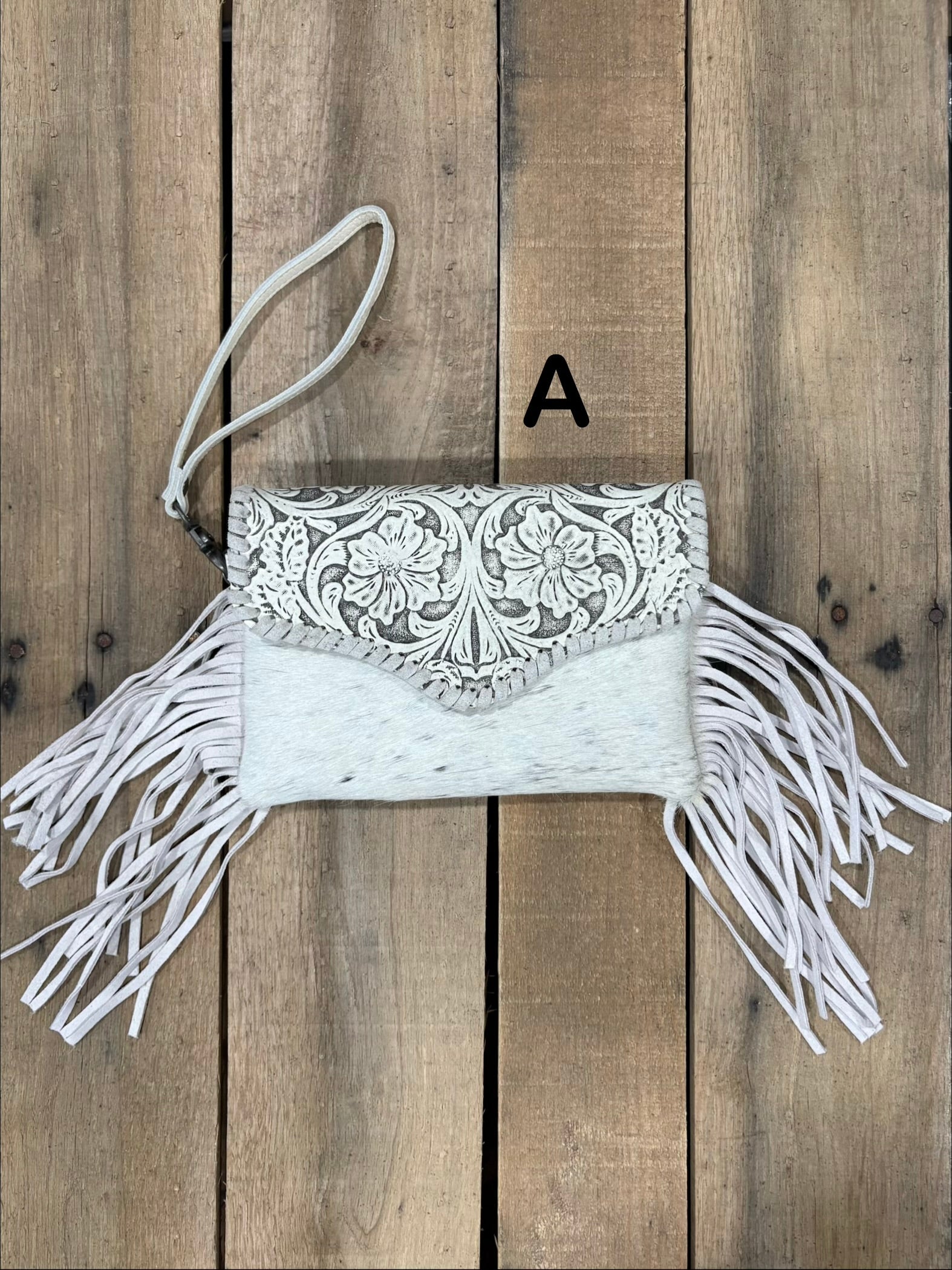 Beige tooled leather and cowhide bag with side fringe. This bag has both a wristlet and should strap. Front View