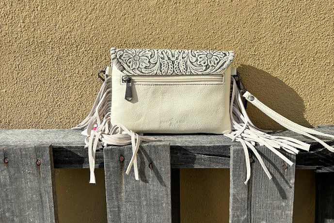 This Beige tooled leather bag can be used as a wristlet or shoulder bag with removable straps. It has side fringe and inside card slots. Rear view showing back zippered pocket. 