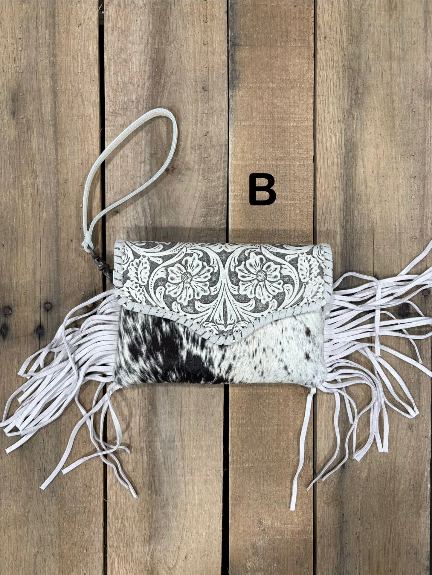 White tooled leather and cowhide bag with side fringe. This bag has both a wristlet and should strap. Front View
