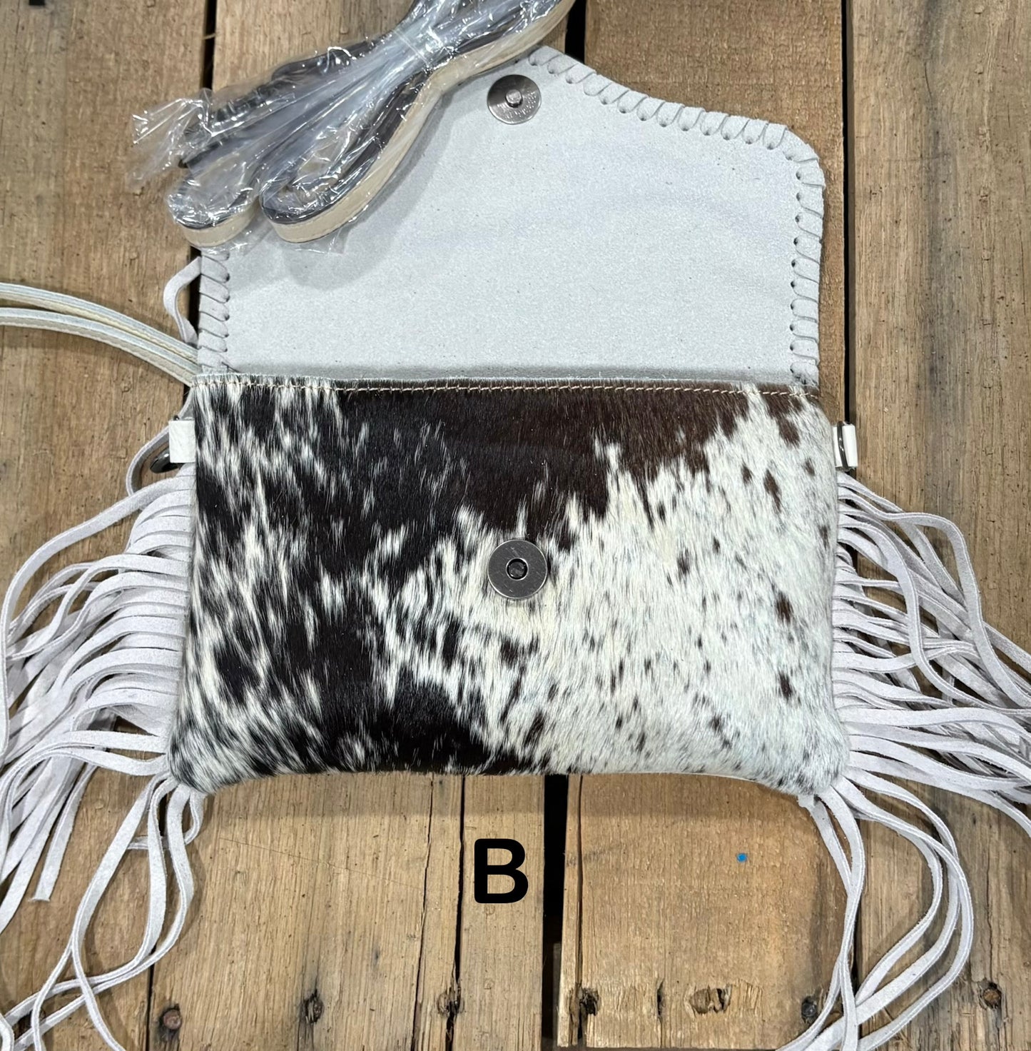 White tooled leather and cowhide bag with side fringe. This bag has both a wristlet and should strap. Front View