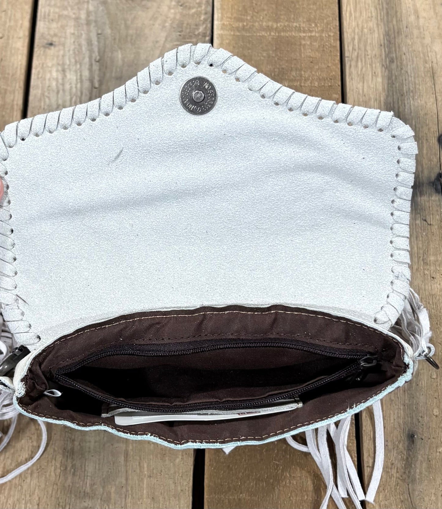 Inside Zipper view of a beige cowhide crossbody purse.