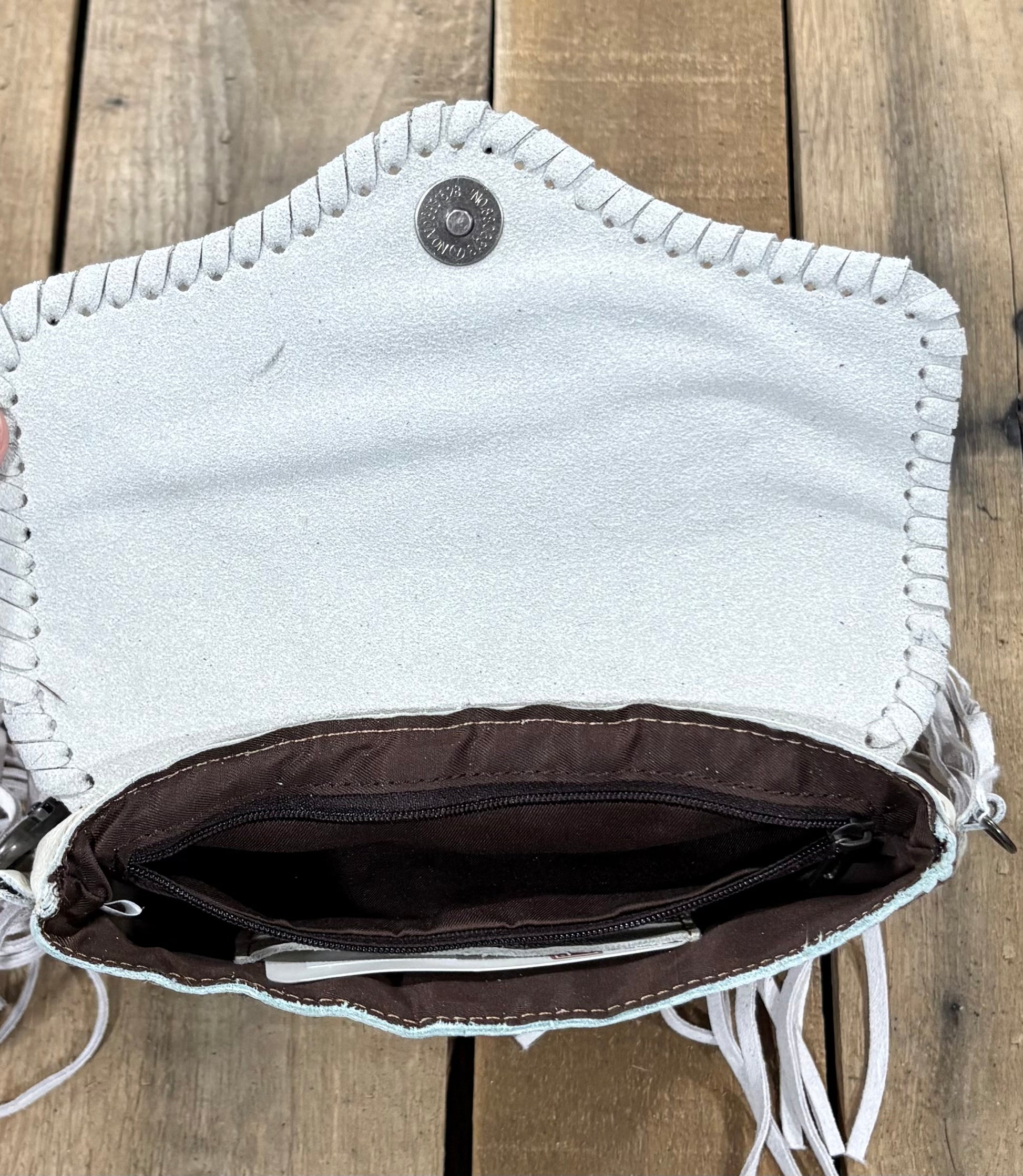 Inside Zipper view of a beige cowhide crossbody purse.