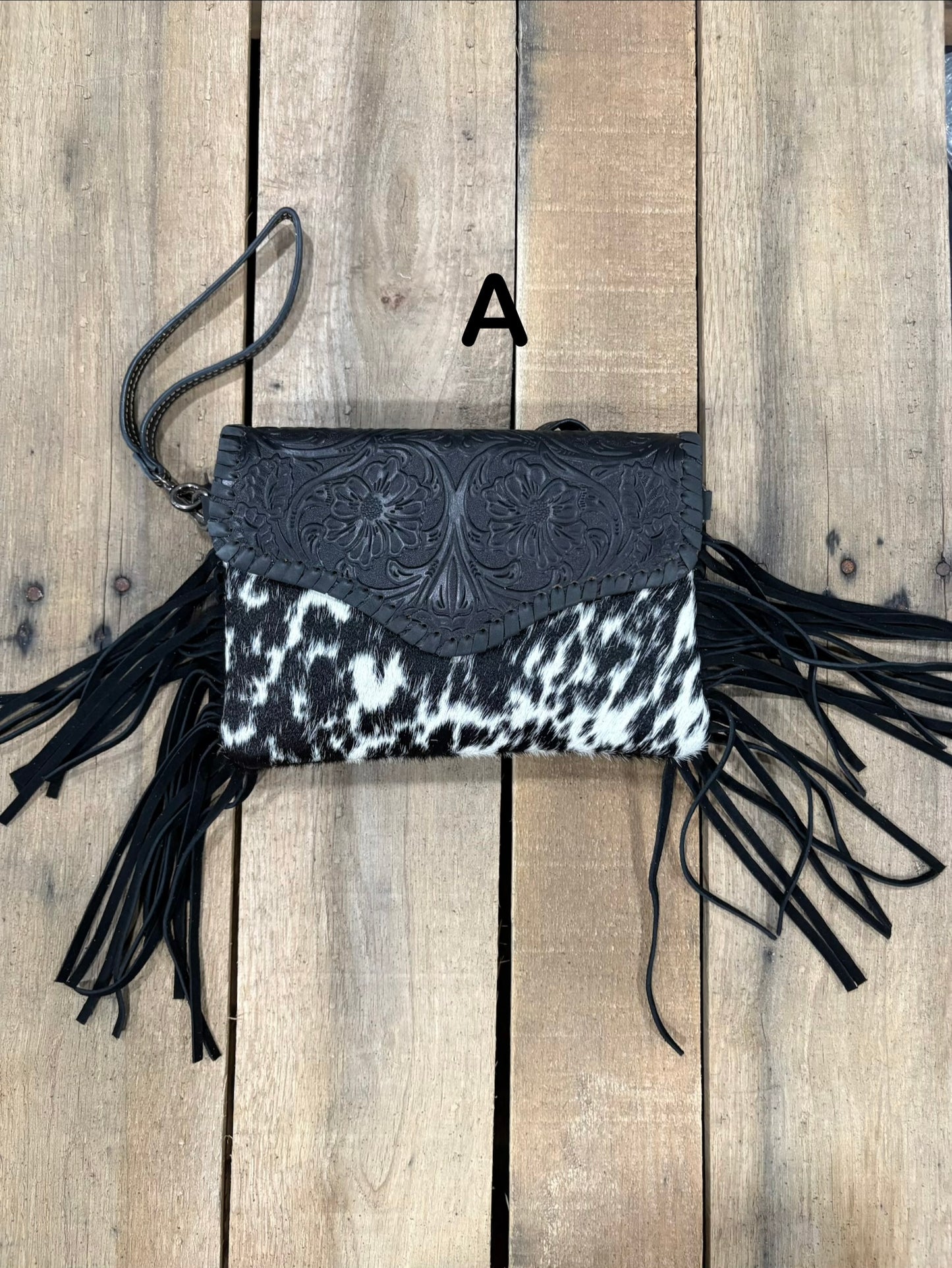 Black tooled leather and cowhide bag with side fringe. This bag has both a wristlet and should strap. Front View