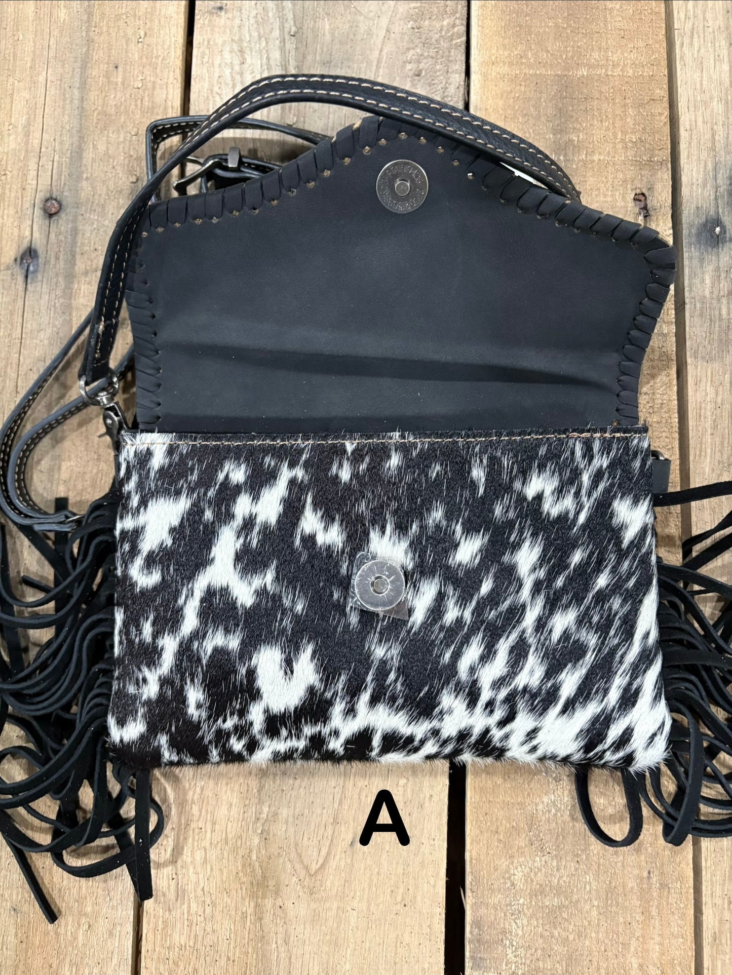 Black tooled leather and cowhide bag with side fringe. This bag has both a wristlet and should strap. Front View