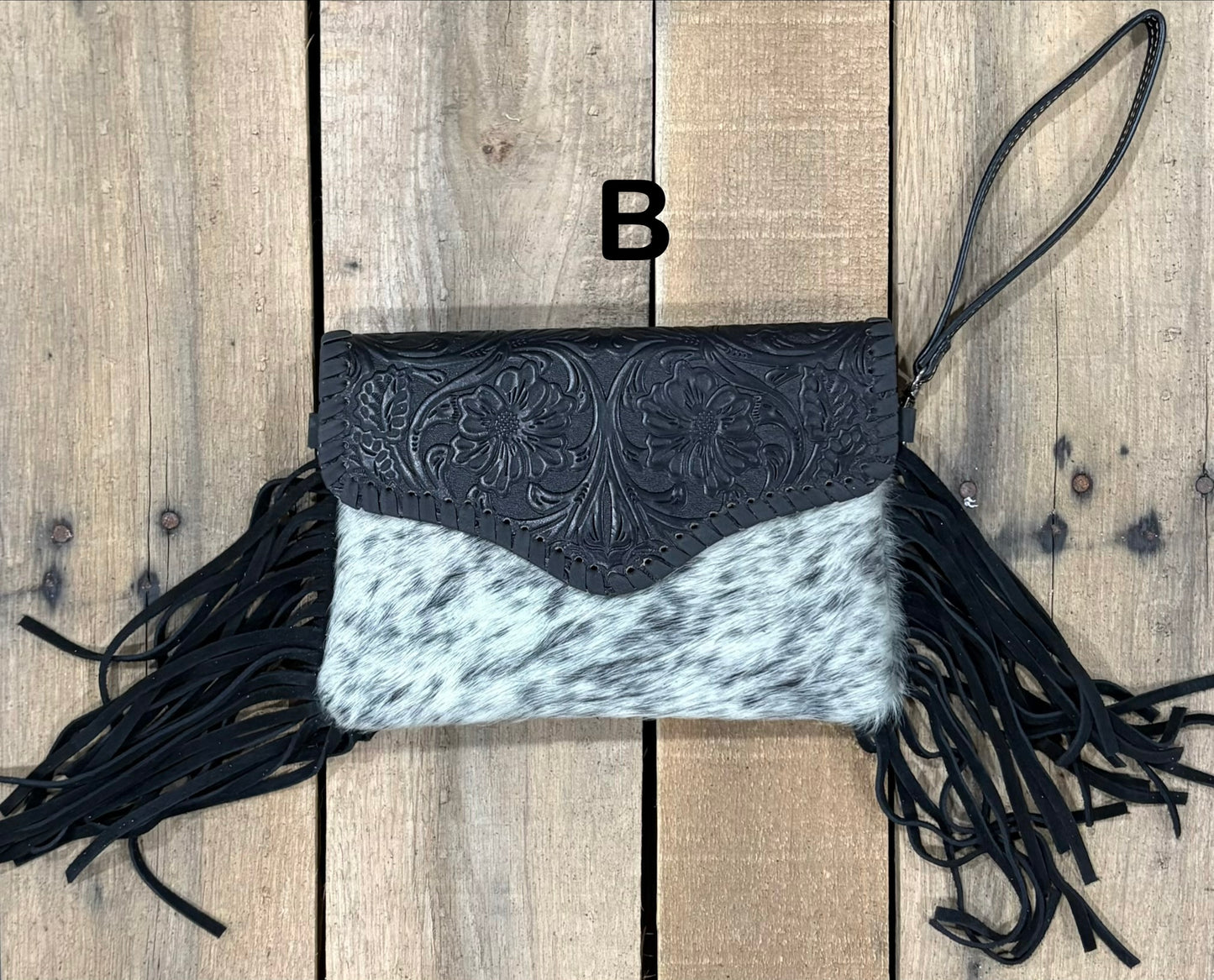 Black tooled leather and cowhide bag with side fringe. This bag has both a wristlet and should strap. Front View