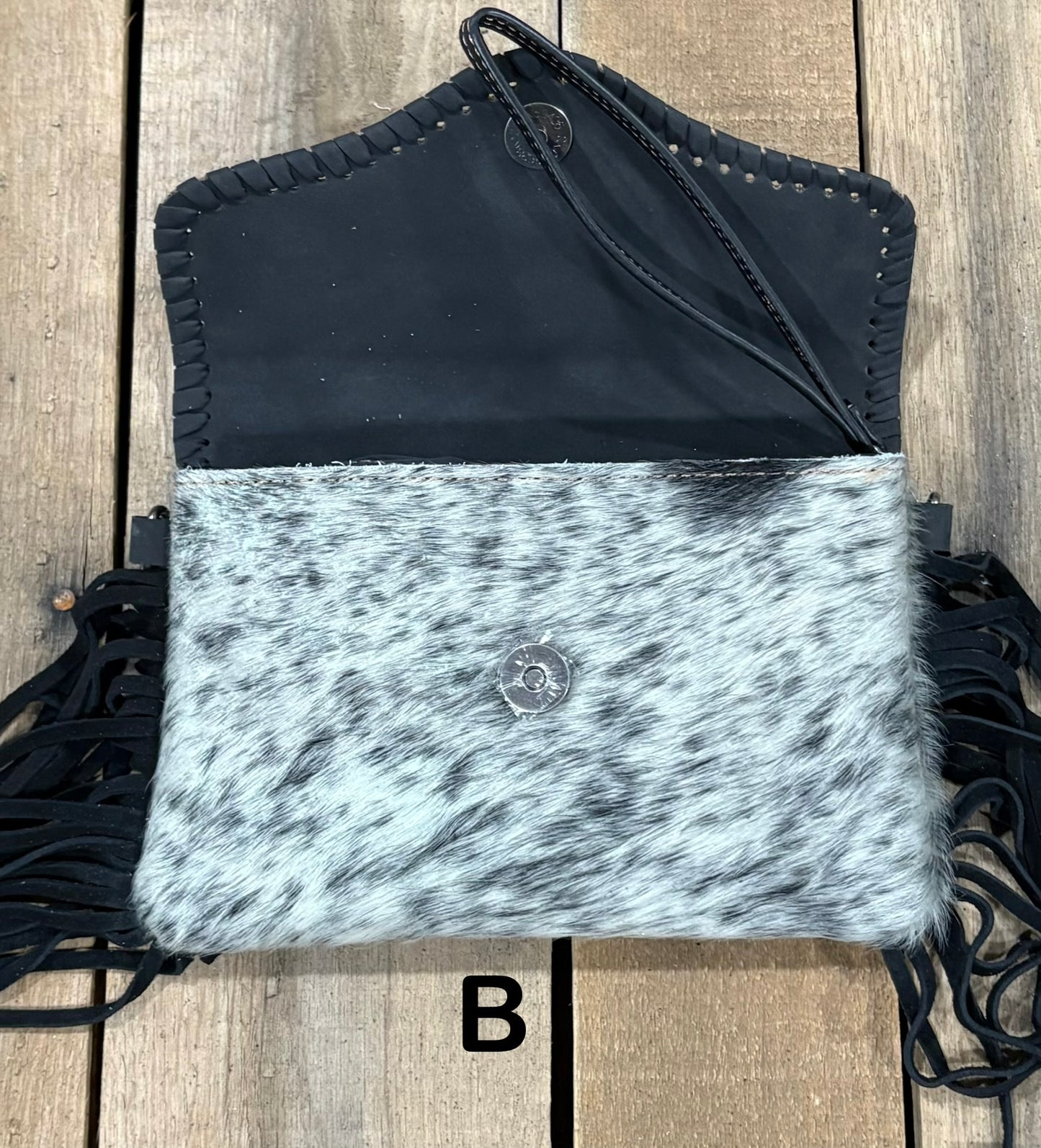 Black tooled leather and cowhide bag with side fringe. This bag has both a wristlet and should strap. Front View
