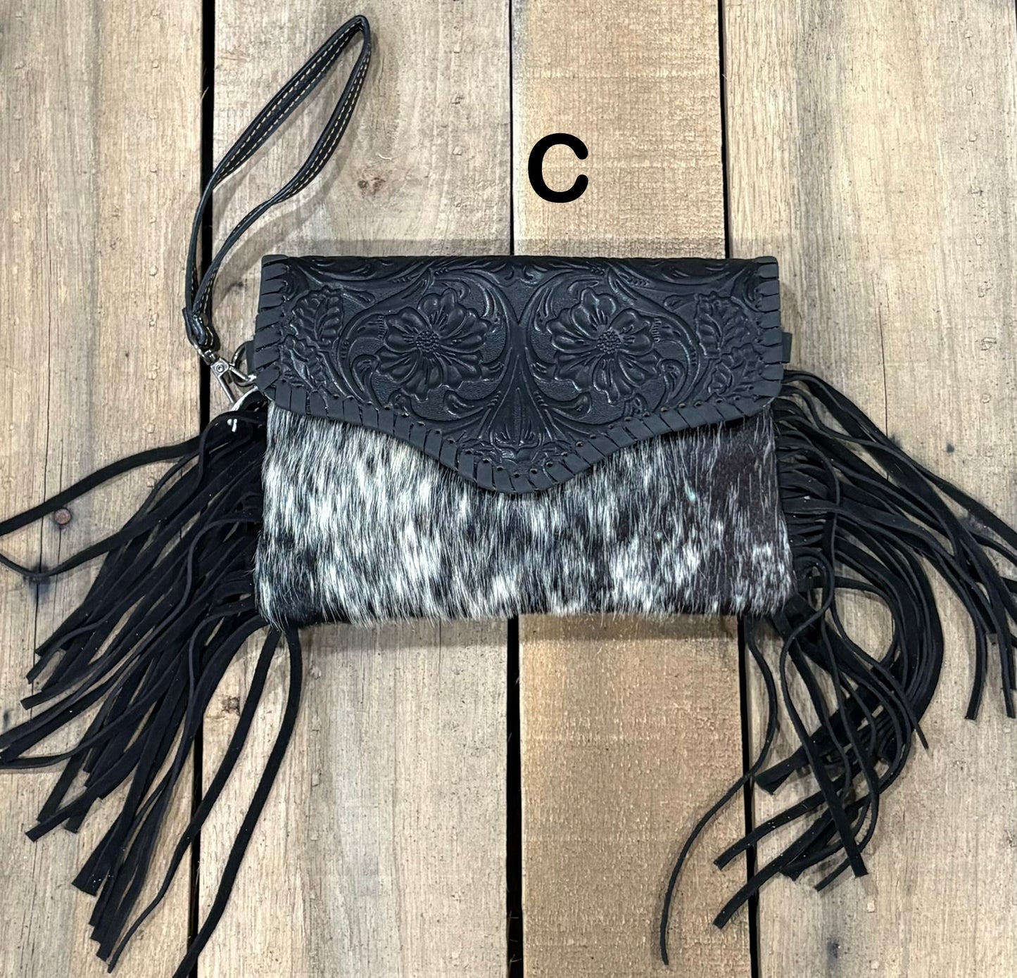 Black tooled leather and cowhide bag with side fringe. This bag has both a wristlet and should strap. Front View