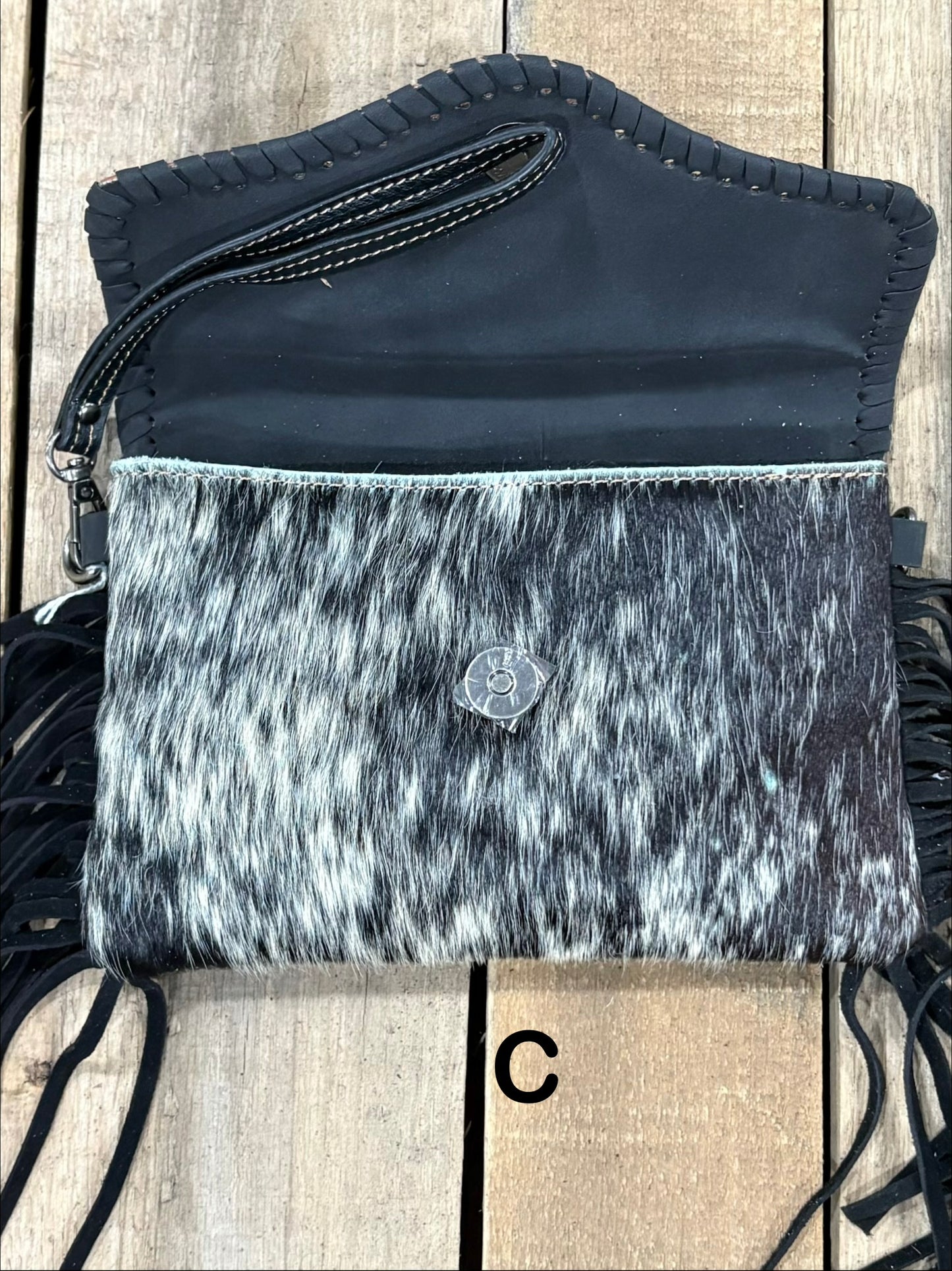 Black tooled leather and cowhide bag with side fringe. This bag has both a wristlet and should strap. Front View