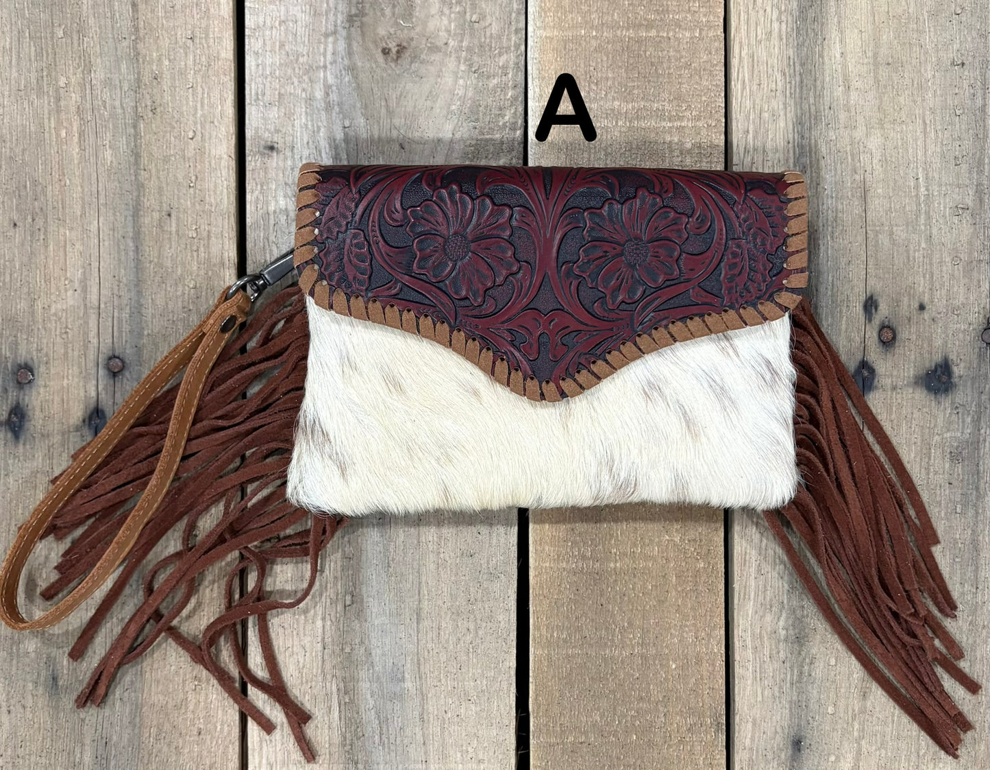 Brown tooled leather and cowhide bag with side fringe. This bag has both a wristlet and should strap. Front View