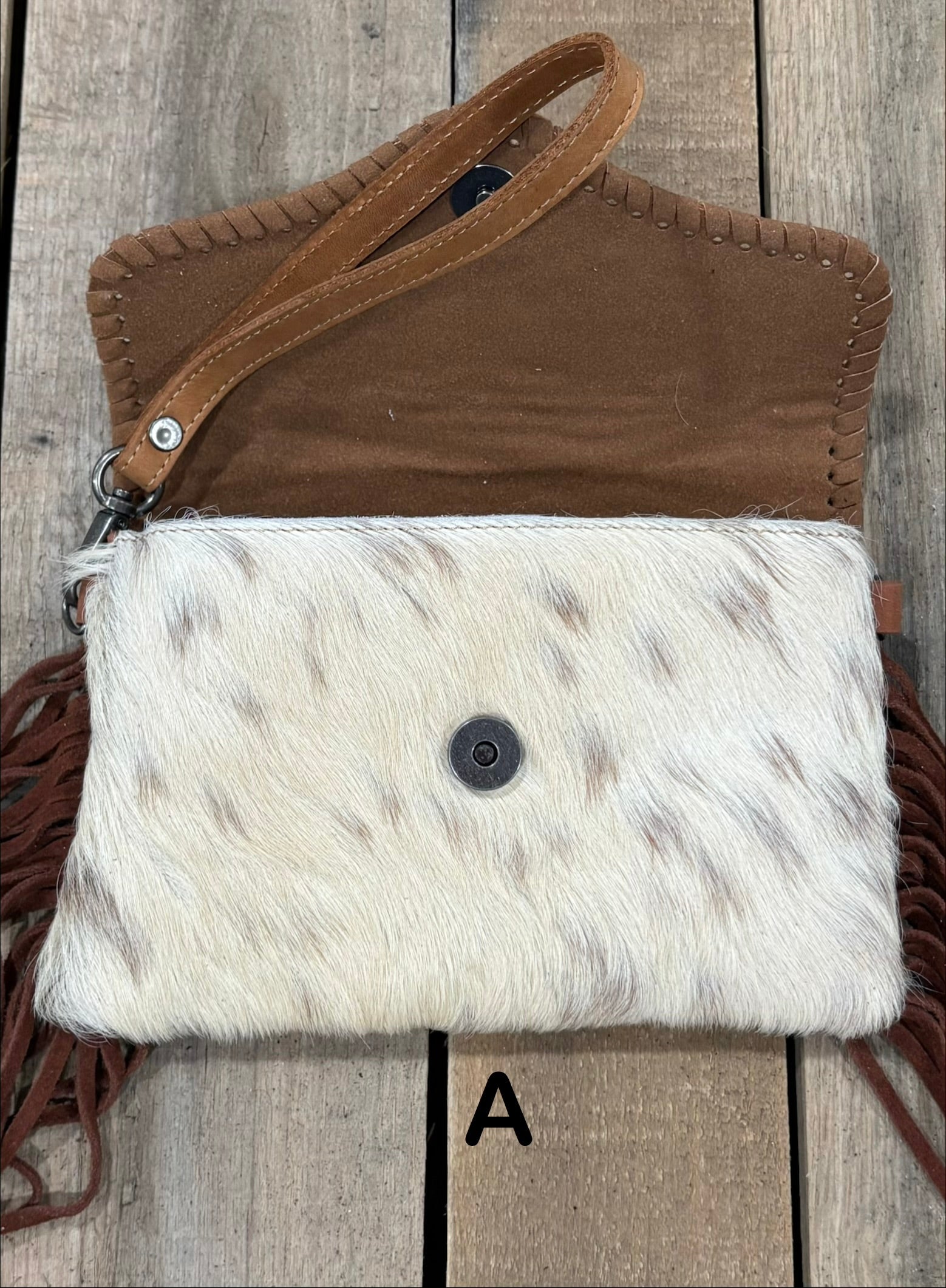 Brown tooled leather and cowhide bag with side fringe. This bag has both a wristlet and should strap. Front View