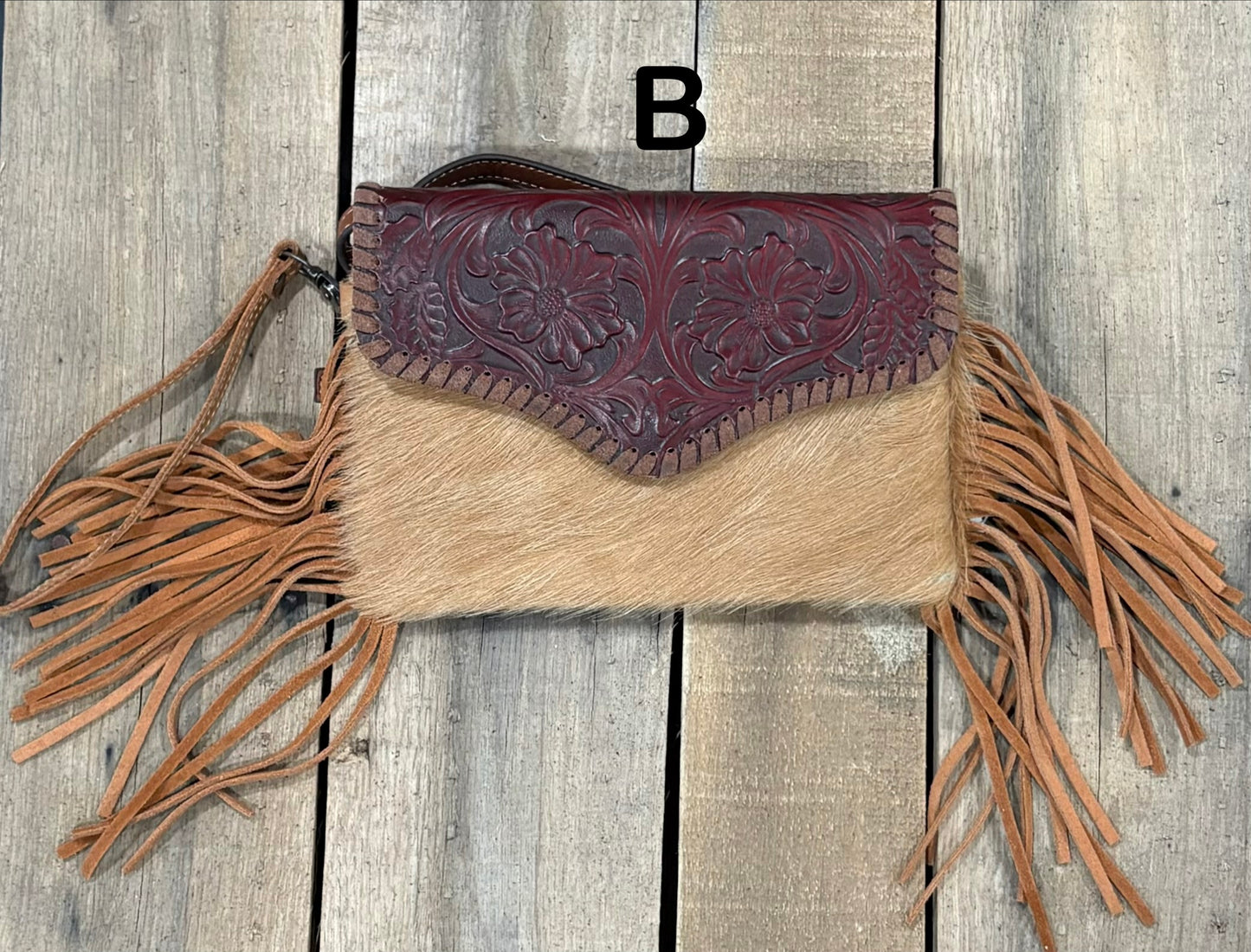 Brown tooled leather and cowhide bag with side fringe. This bag has both a wristlet and should strap. Front View