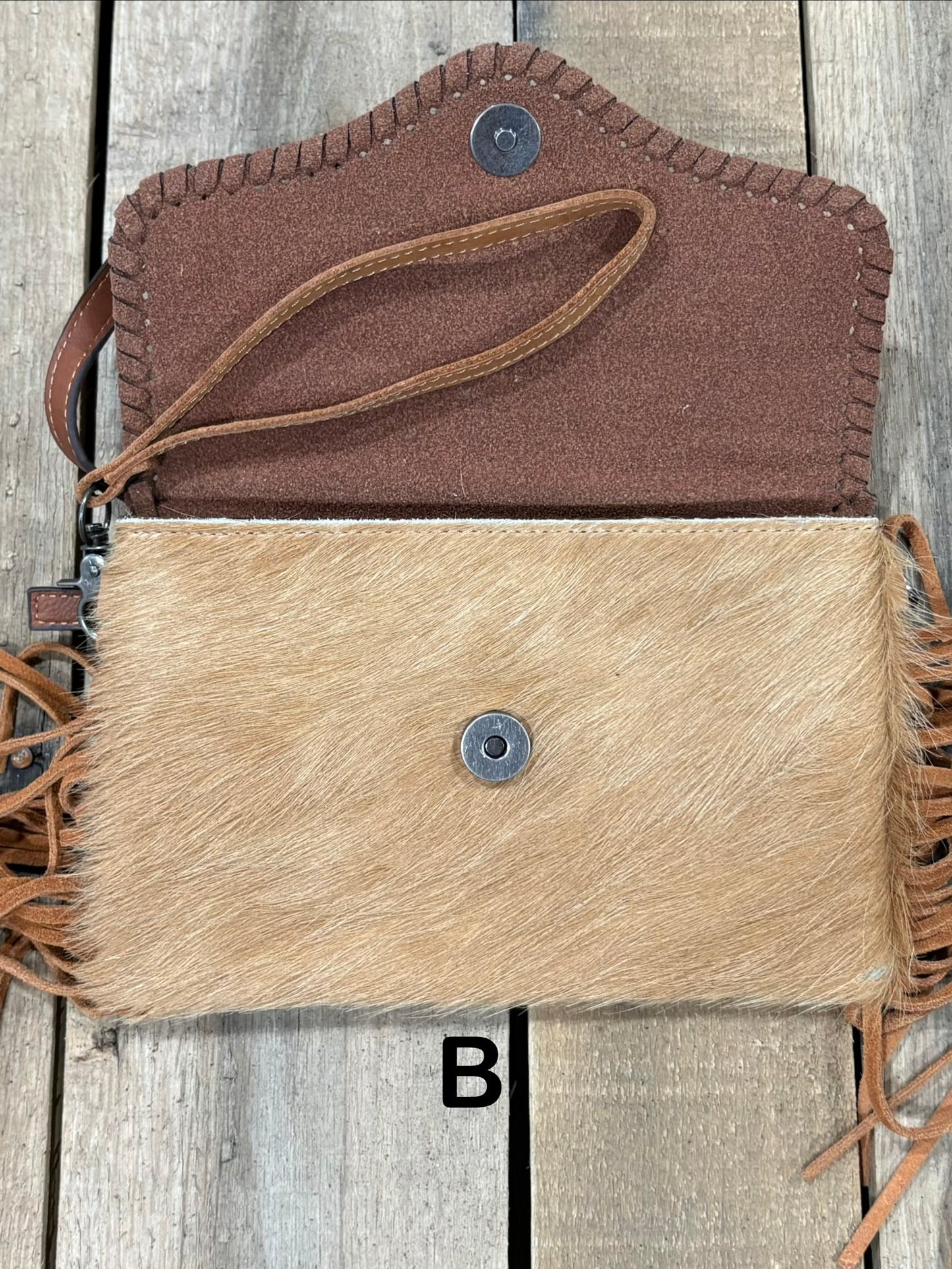 Brown tooled leather and cowhide bag with side fringe. This bag has both a wristlet and should strap. Front View