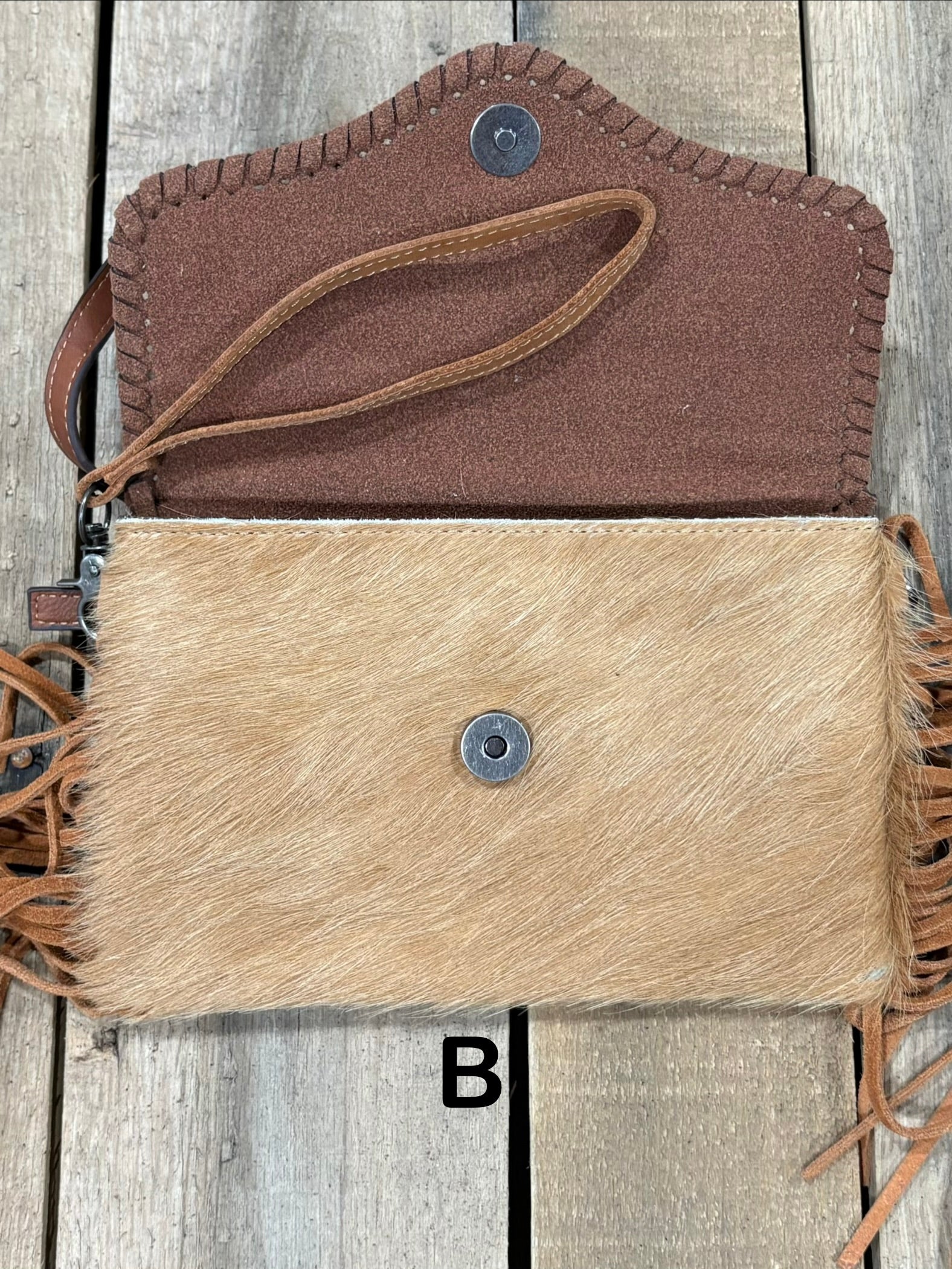 Brown tooled leather and cowhide bag with side fringe. This bag has both a wristlet and should strap. Front View