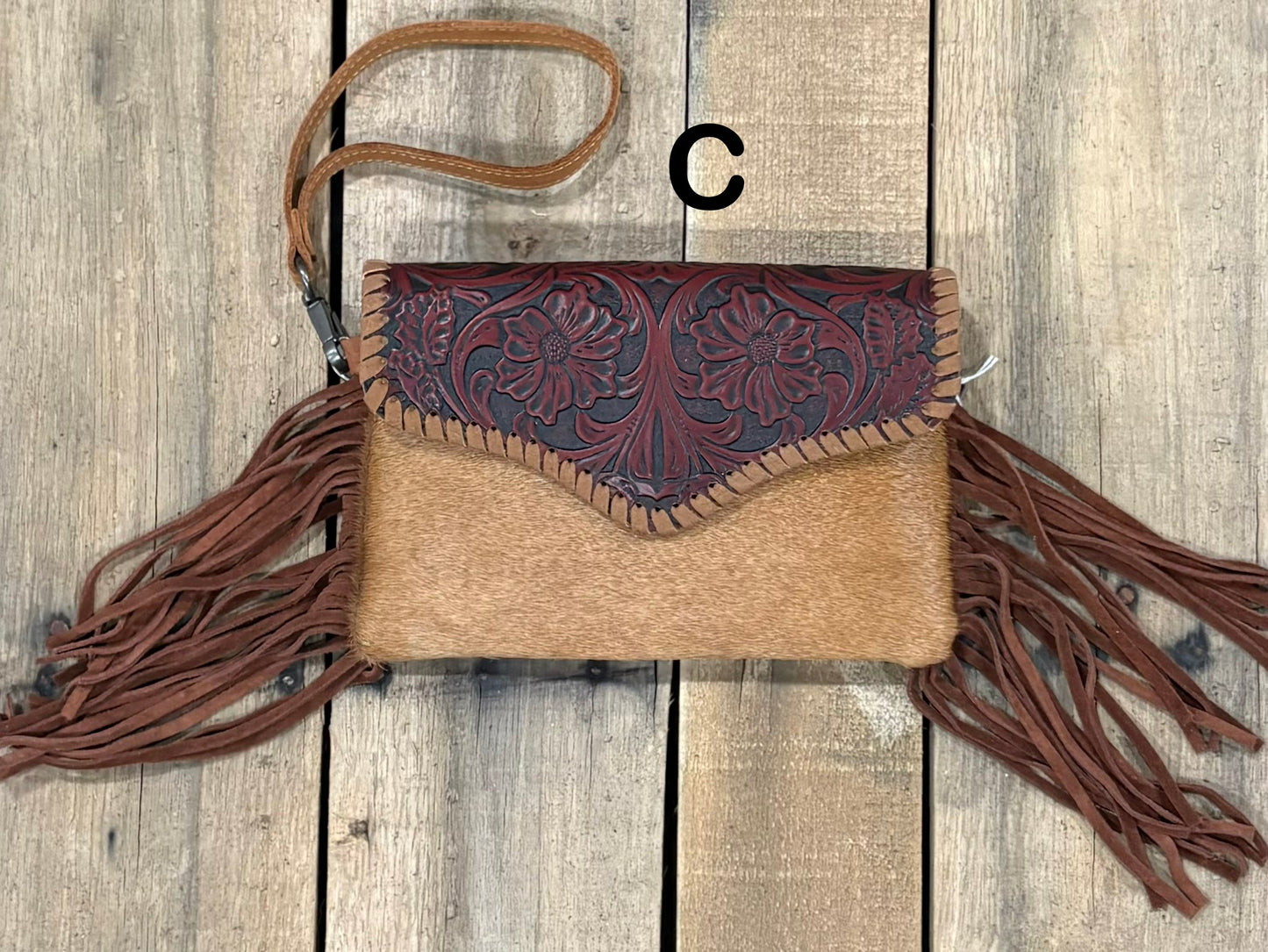 Brown tooled leather and cowhide bag with side fringe. This bag has both a wristlet and should strap. Front View