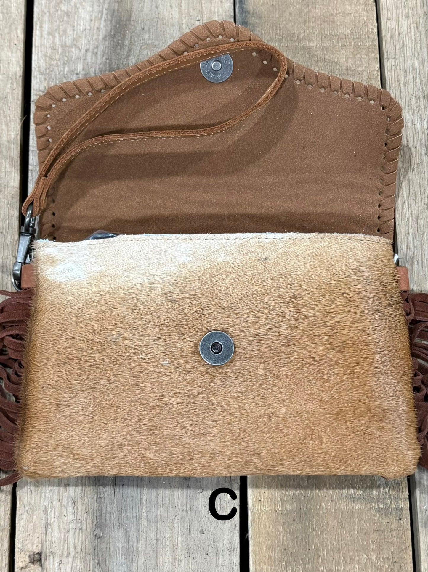 Brown tooled leather and cowhide bag with side fringe. This bag has both a wristlet and should strap. Front View
