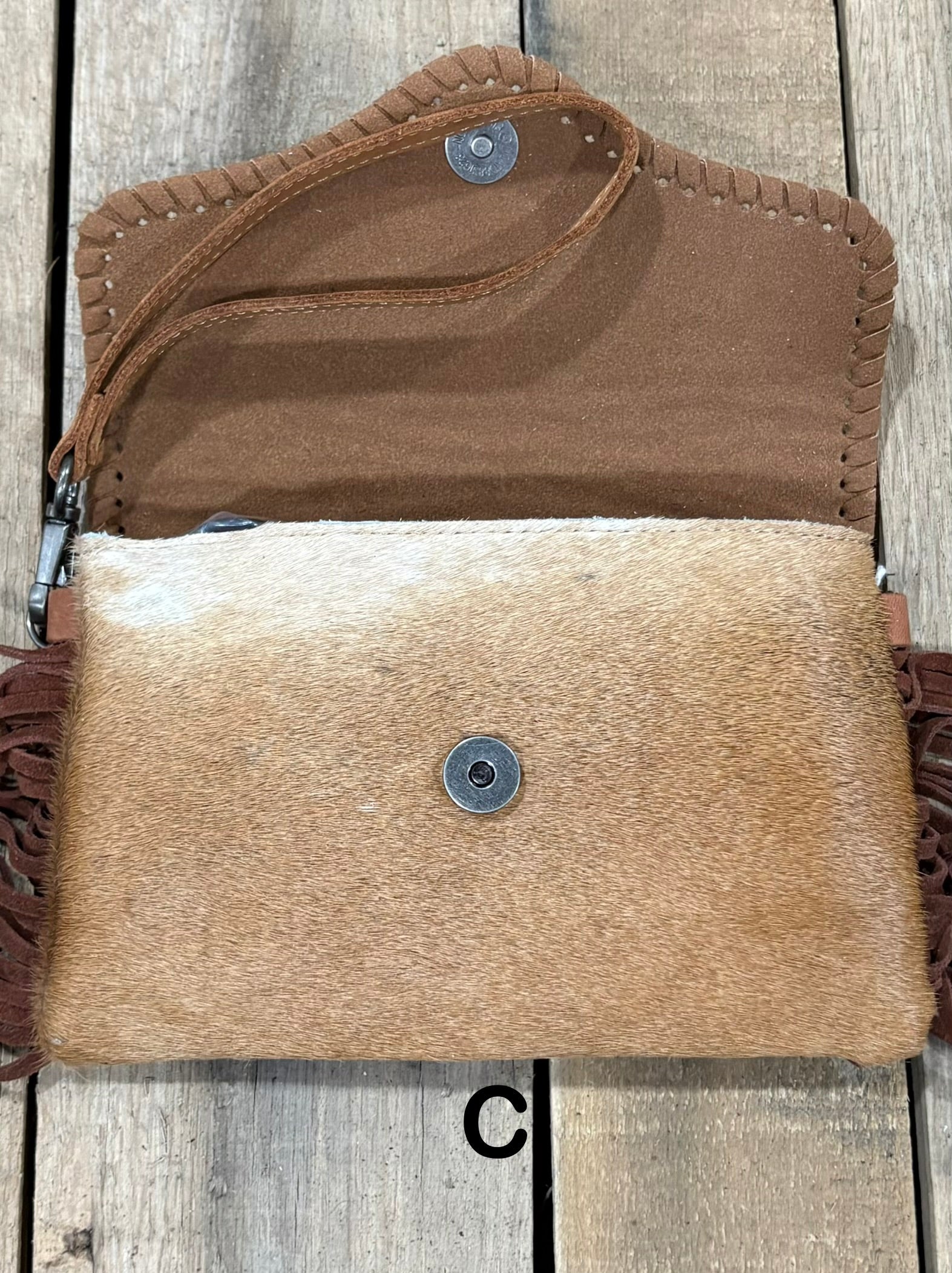 Brown tooled leather and cowhide bag with side fringe. This bag has both a wristlet and should strap. Front View