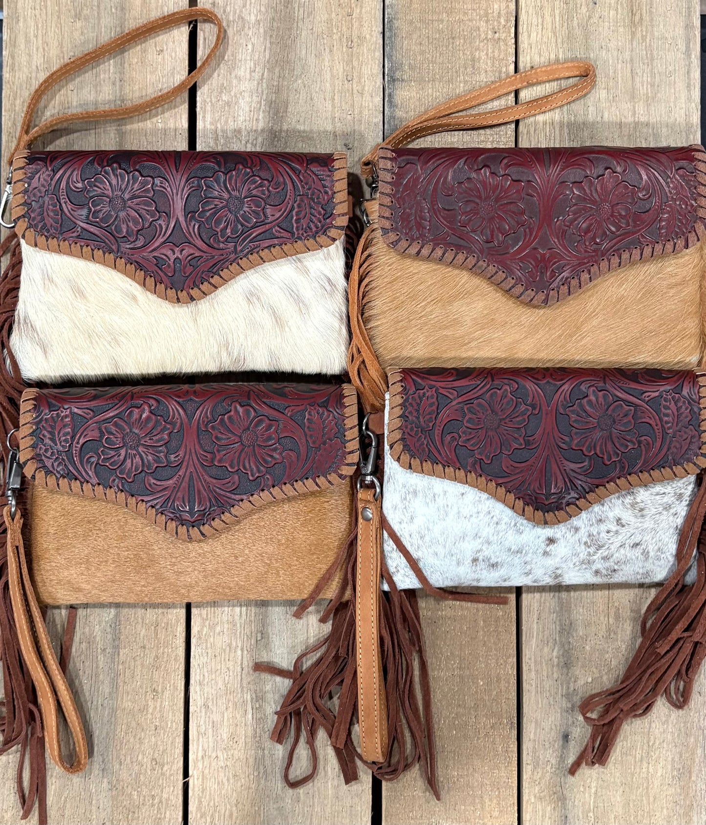 Four leather handbags with intricate designs on a wooden surface
