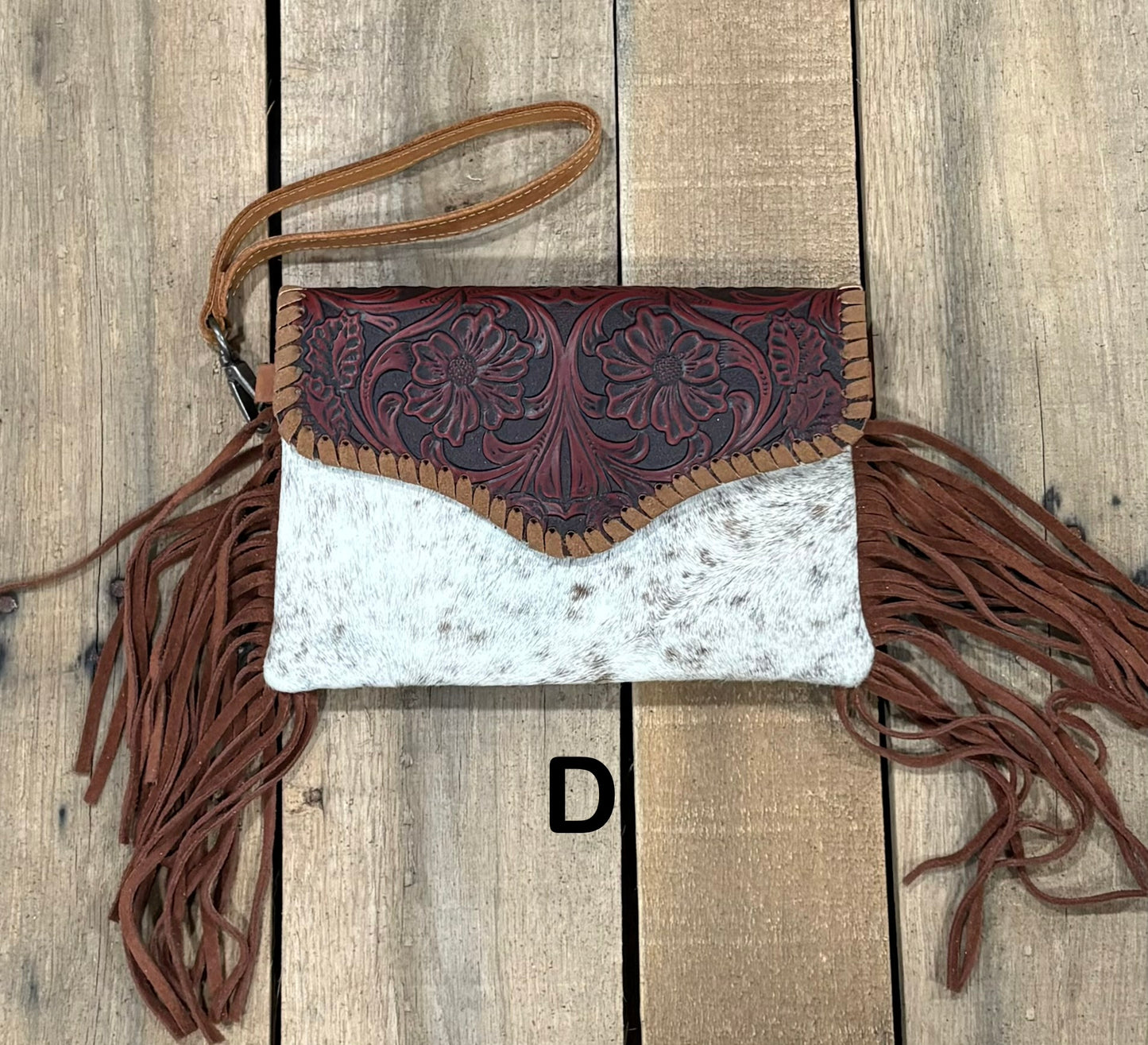 Brown tooled leather and cowhide bag with side fringe. This bag has both a wristlet and should strap. Front View
